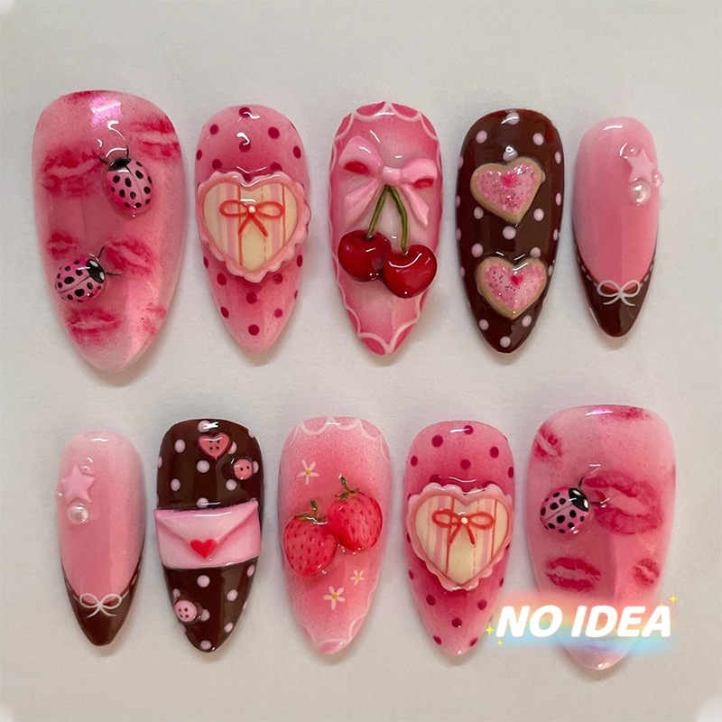 Sweet pink almond shaped nails with cute strawberry, cherry, heart, and bow illustrations.