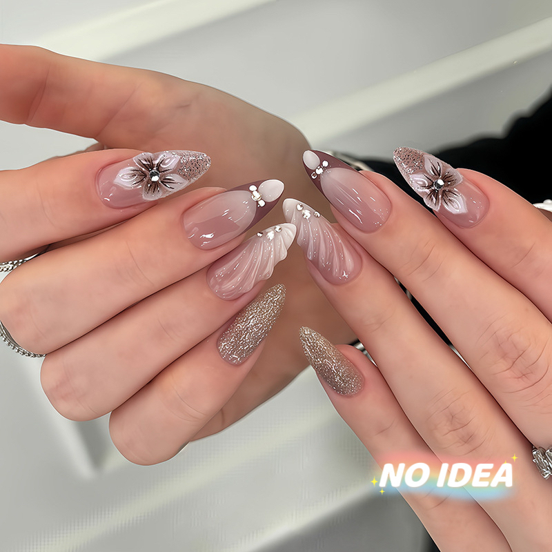 Almond shaped nails with a nude/white French tip and metallic pearl & seashell embellishments.