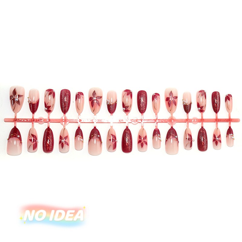 Set of short almond shaped press on nails in wine red with metallic silver floral designs, arrayed by size.