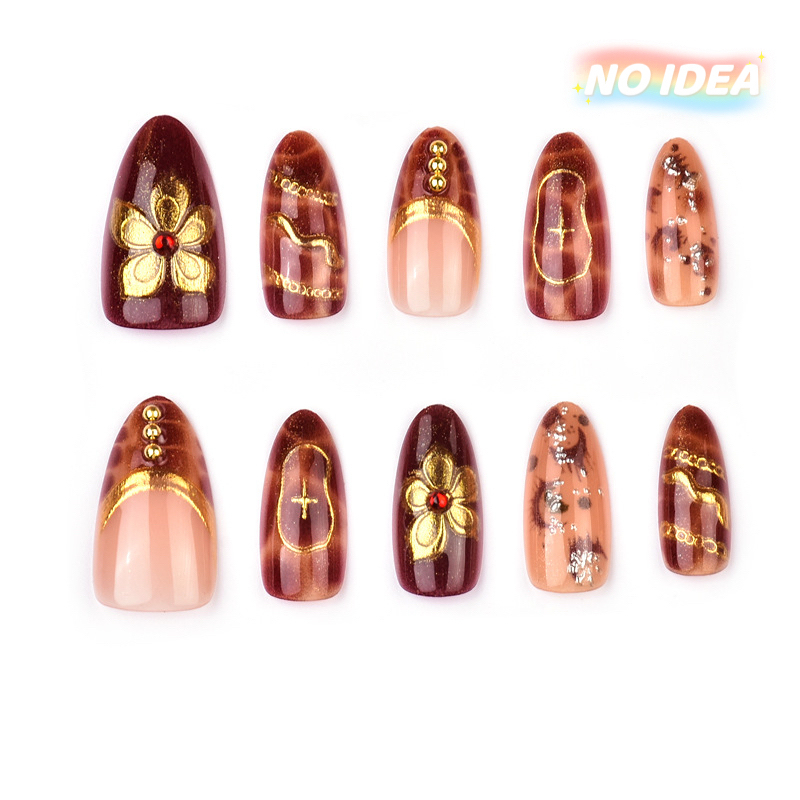 Short almond shaped press on nails in wine red with detailed gold or silver metallic floral patterns.