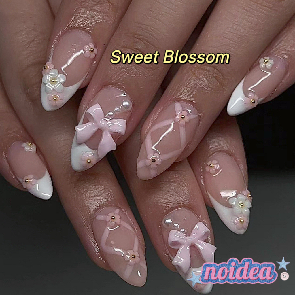 24 pieces of short almond-shaped press on nails with pink and white floral design, shown with jelly glue and tool, laid out to display 12 sizes