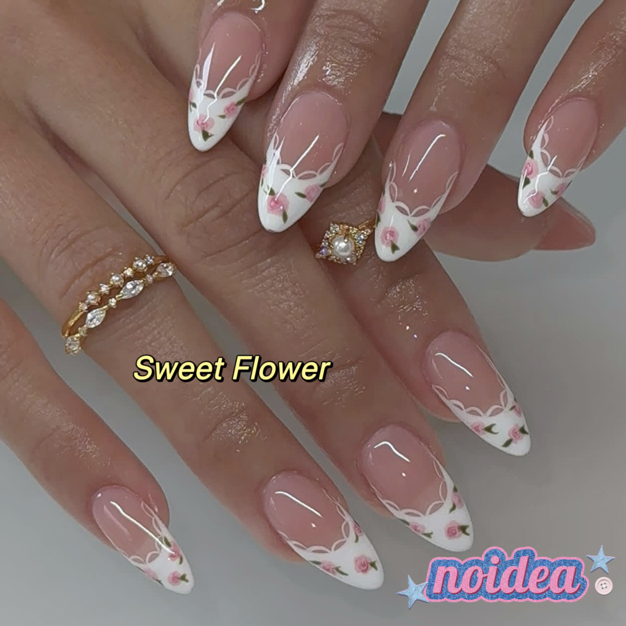 24 pieces of short almond-shaped press on nails with pink and white floral design, shown with jelly glue and tool, laid out to display 12 sizes