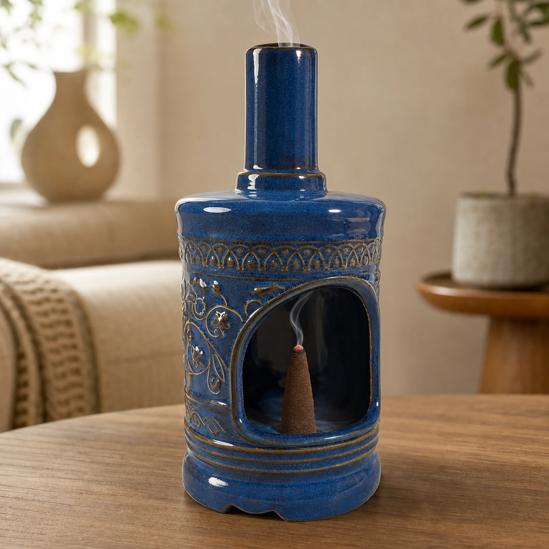 Blue ceramic incense burner with a tapered cone ember and smoke rising through the chimney
