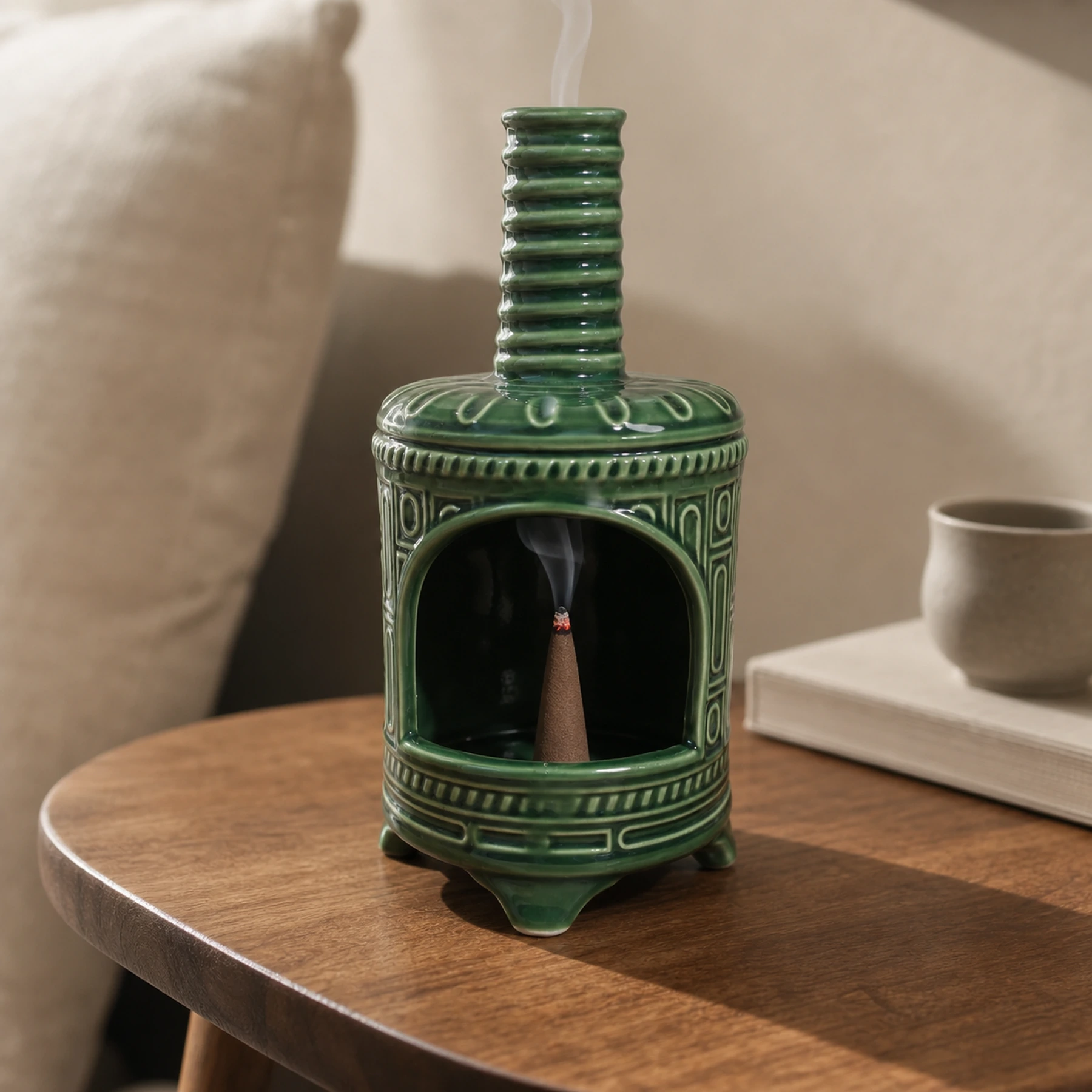 Green ceramic incense burner with a tapered cone ember and smoke rising through the chimney