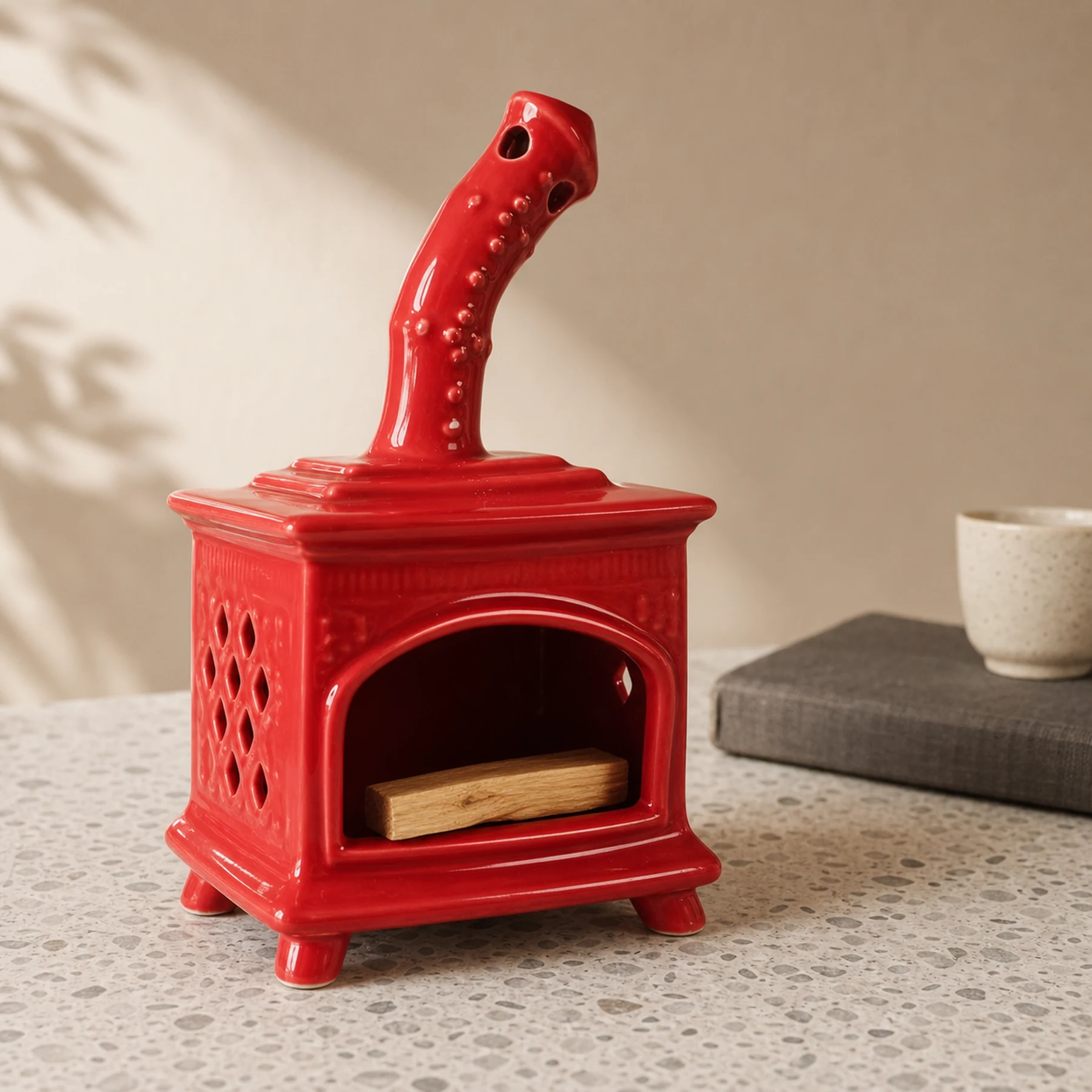 Red ceramic fireplace incense holder with unlit Palo Santo placed in the open hearth