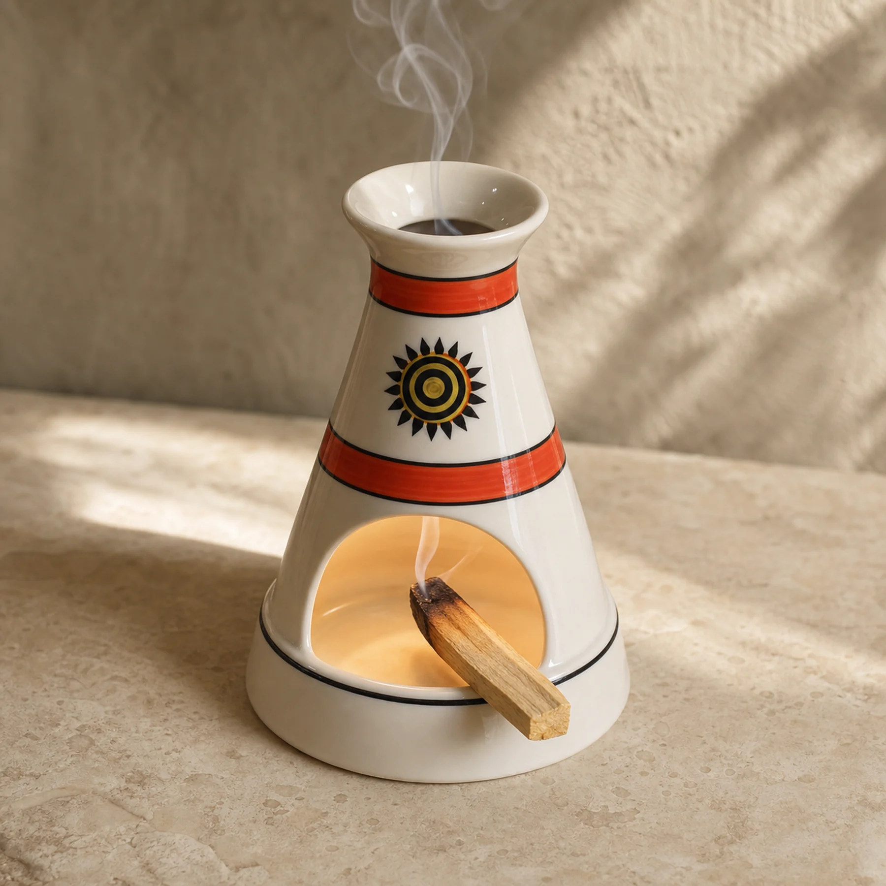 White ceramic sun motif Palo Santo holder with a smoldering wood stick inside