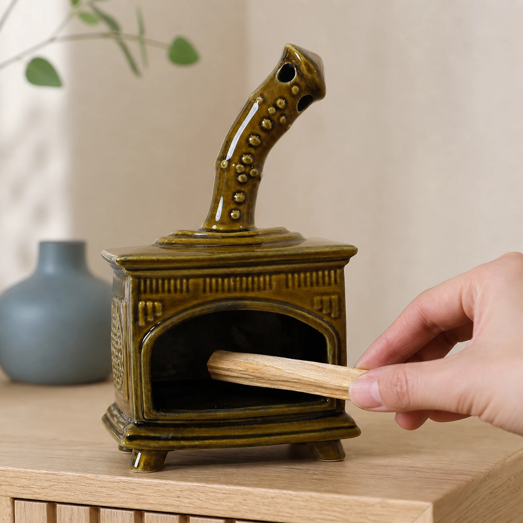 Brown ceramic fireplace incense holder with a hand placing unlit Palo Santo for scale