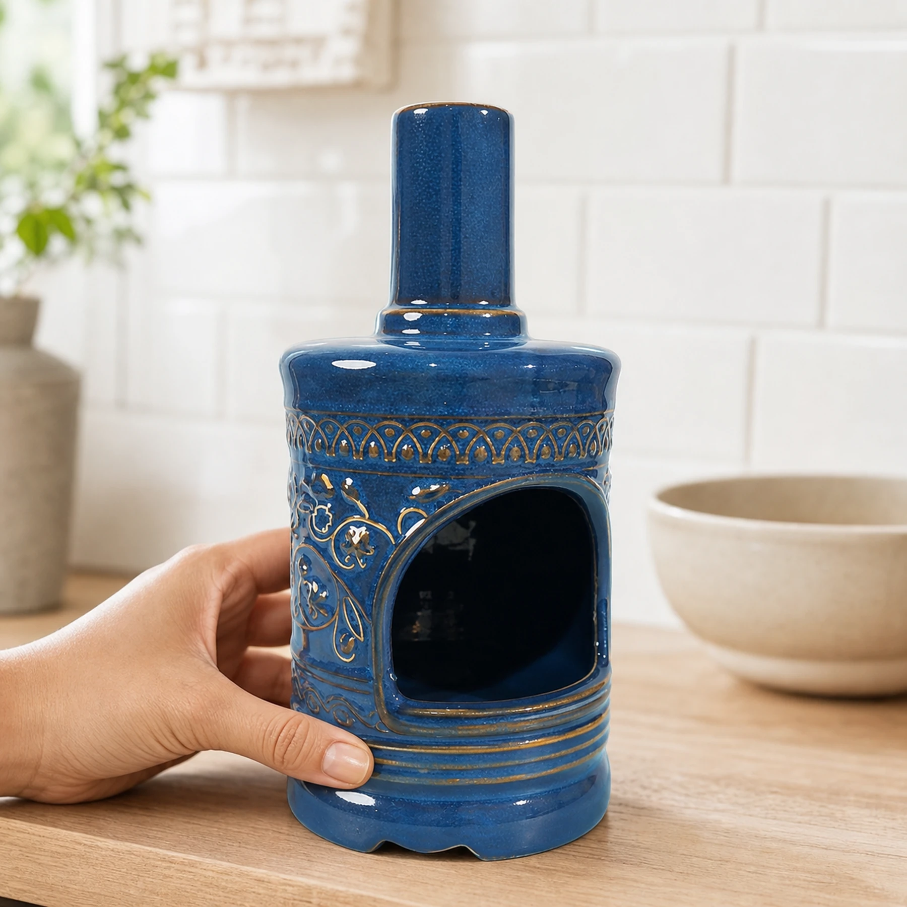 Blue ceramic incense burner shown with an adult hand for tabletop scale