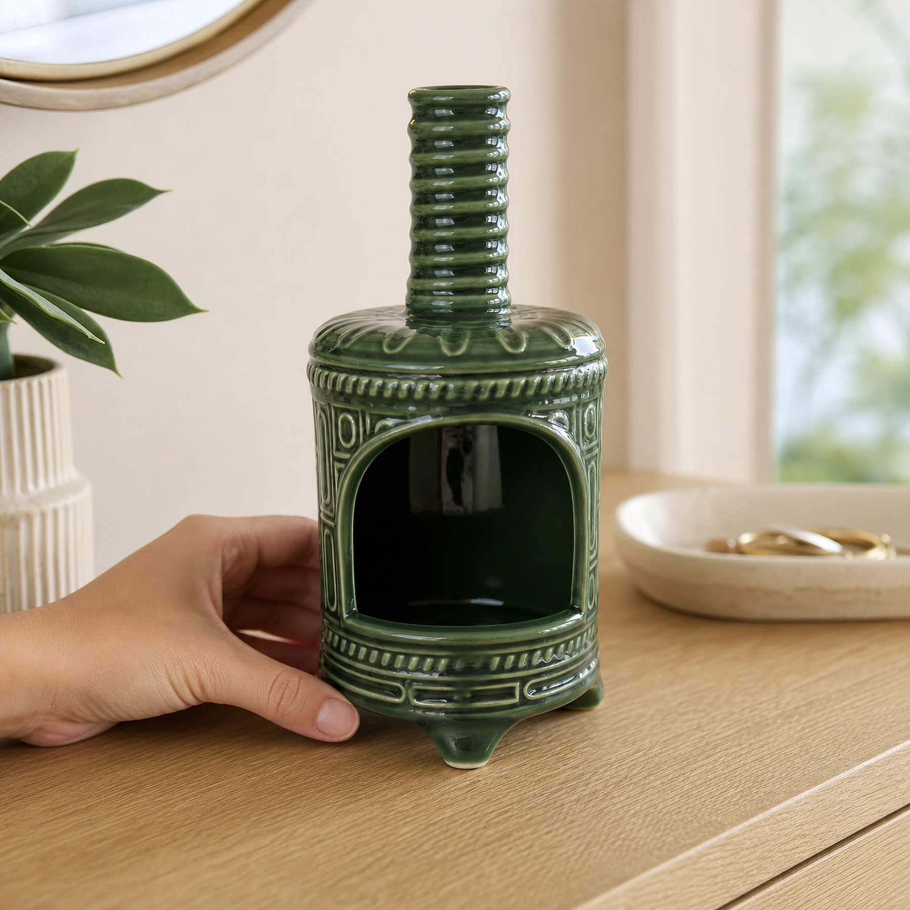 Green ceramic incense burner shown with an adult hand for tabletop scale