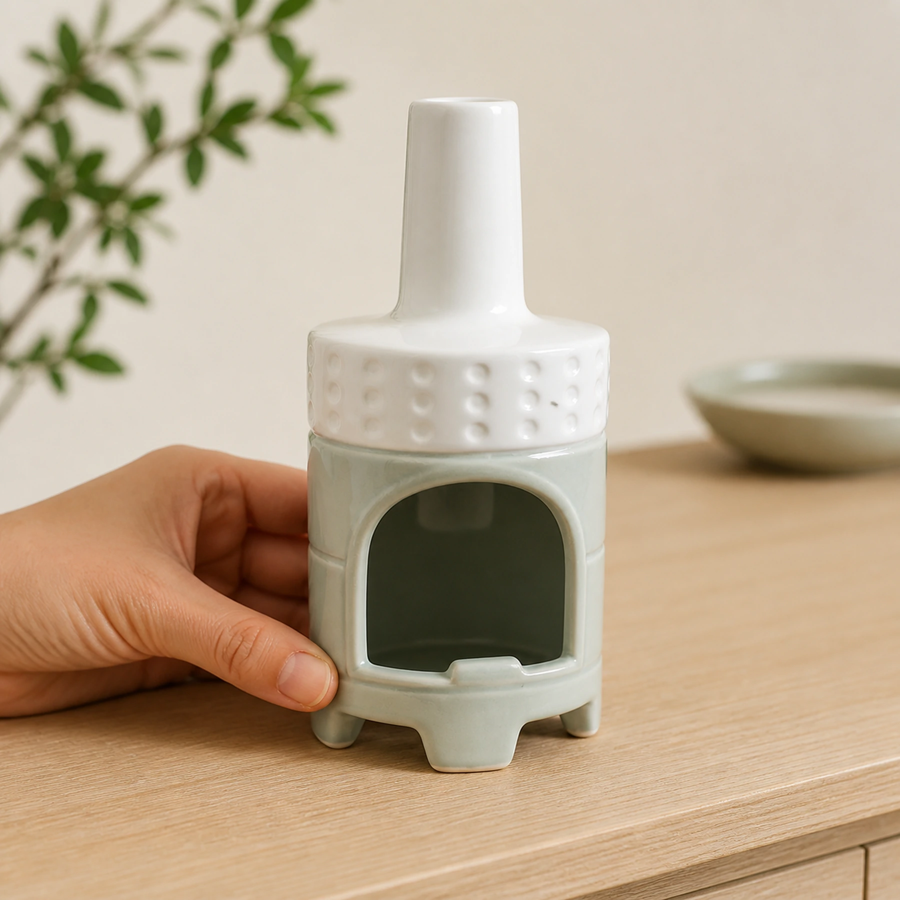 White Green ceramic incense burner shown with an adult hand for tabletop scale
