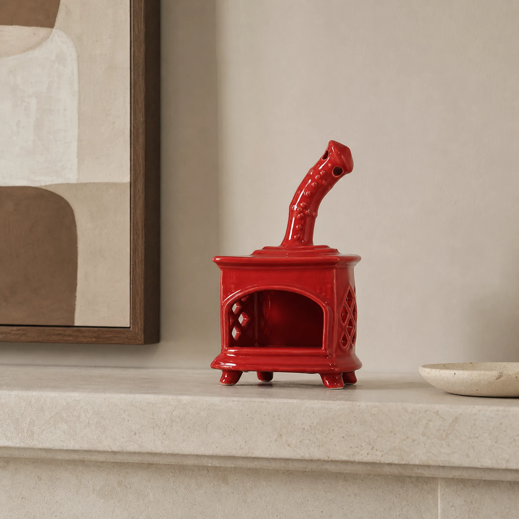 Red ceramic fireplace incense holder styled on a home mantel shelf