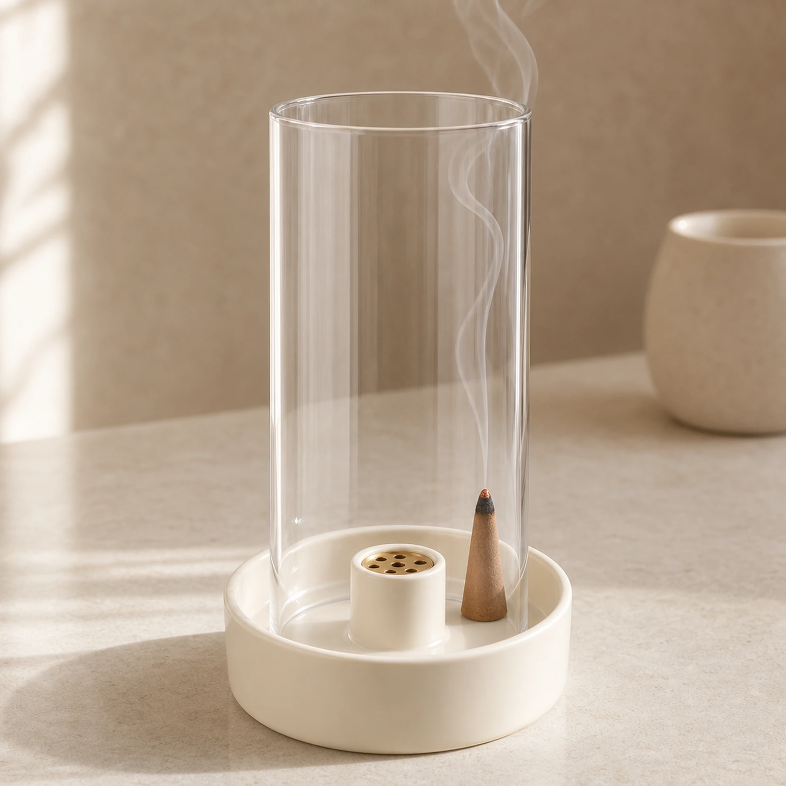 Ivory ceramic incense burner with a lit tapered cone and smoke inside the clear glass cover