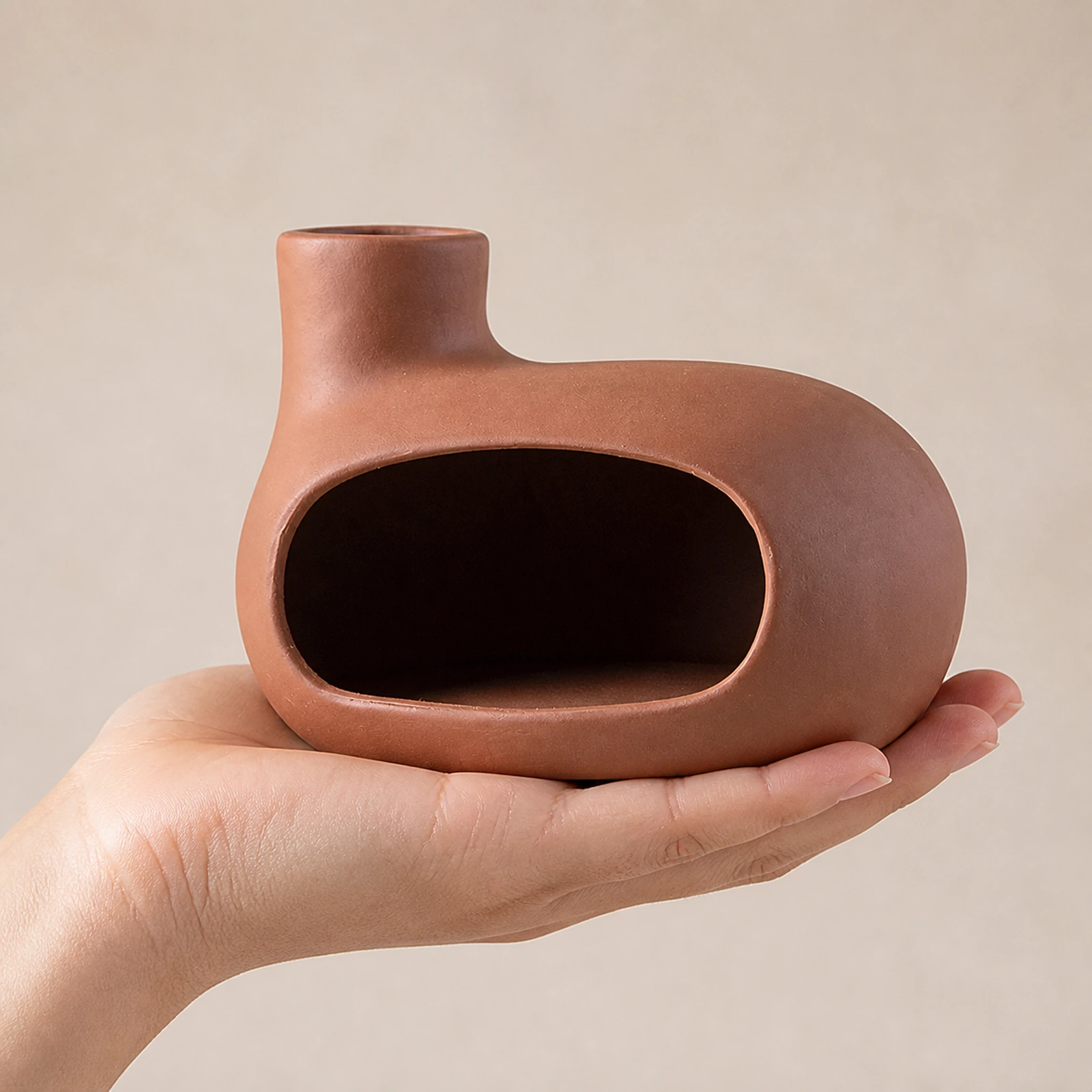 Auburn red Classic Ceramic Palo Santo & Sage Burner, held in an adult hand to show approximate tabletop scale.