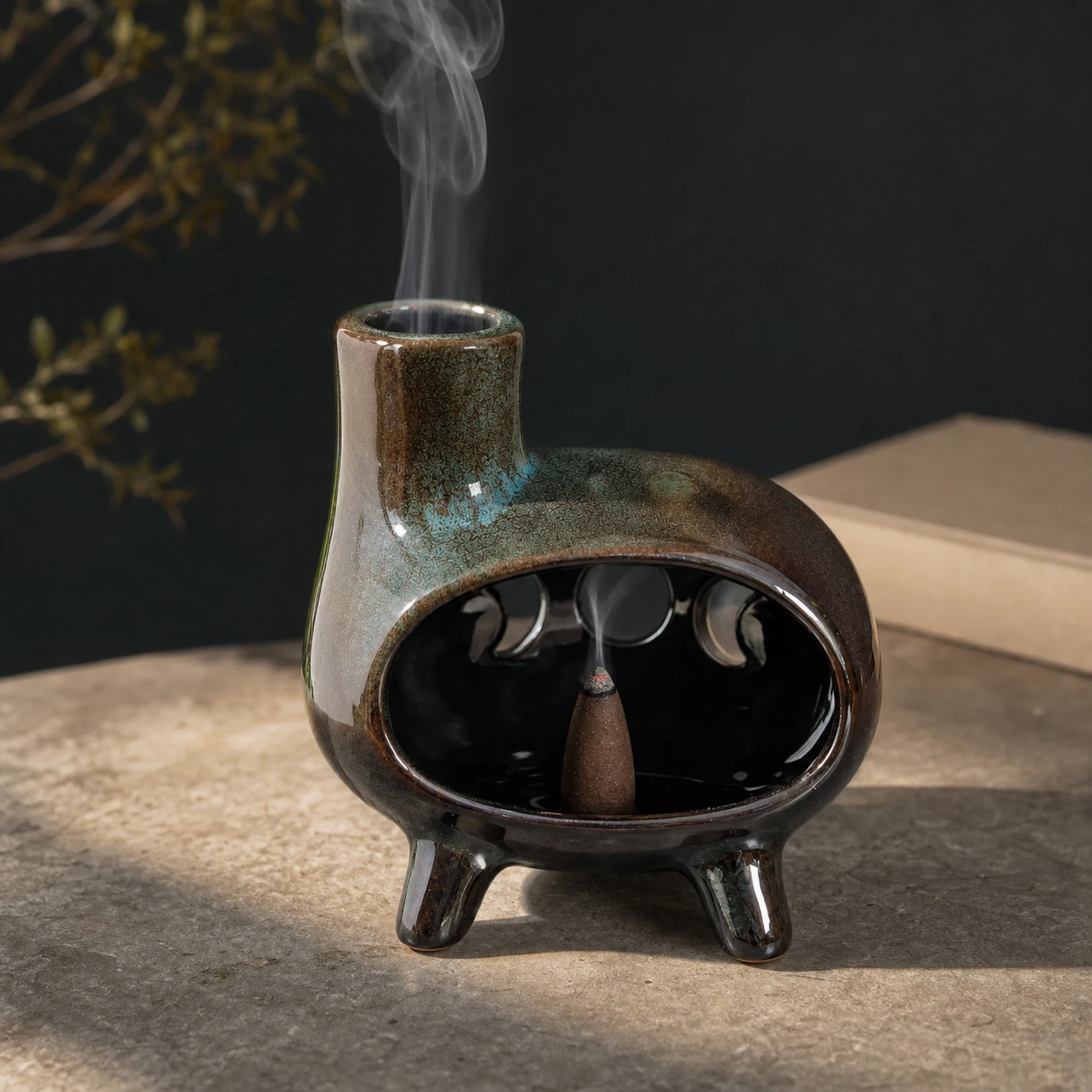 Green glaze ceramic Palo Santo holder with a tapered incense cone and smoke from the chimney