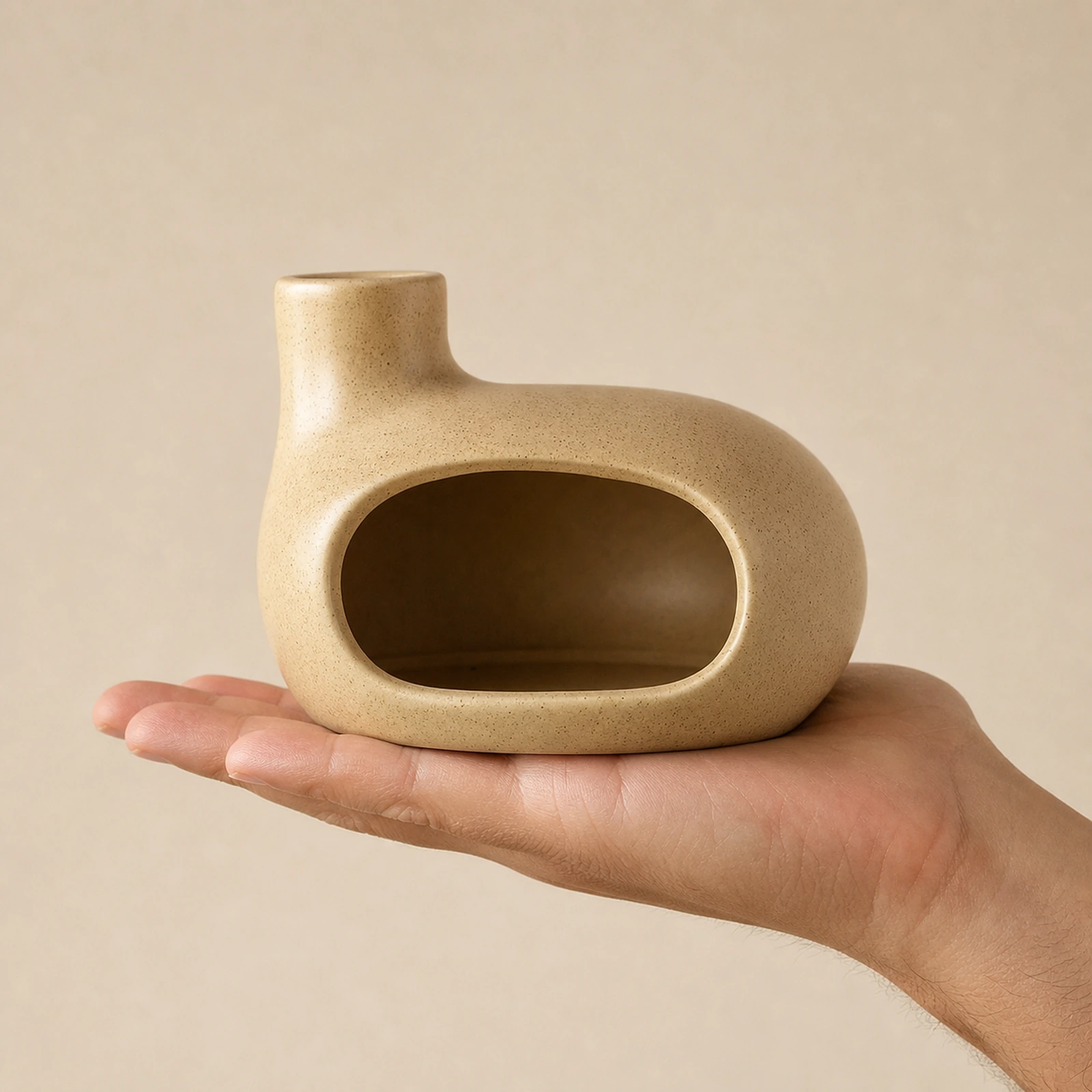 Beige Classic Ceramic Palo Santo & Sage Burner, held in an adult hand to show approximate tabletop scale.