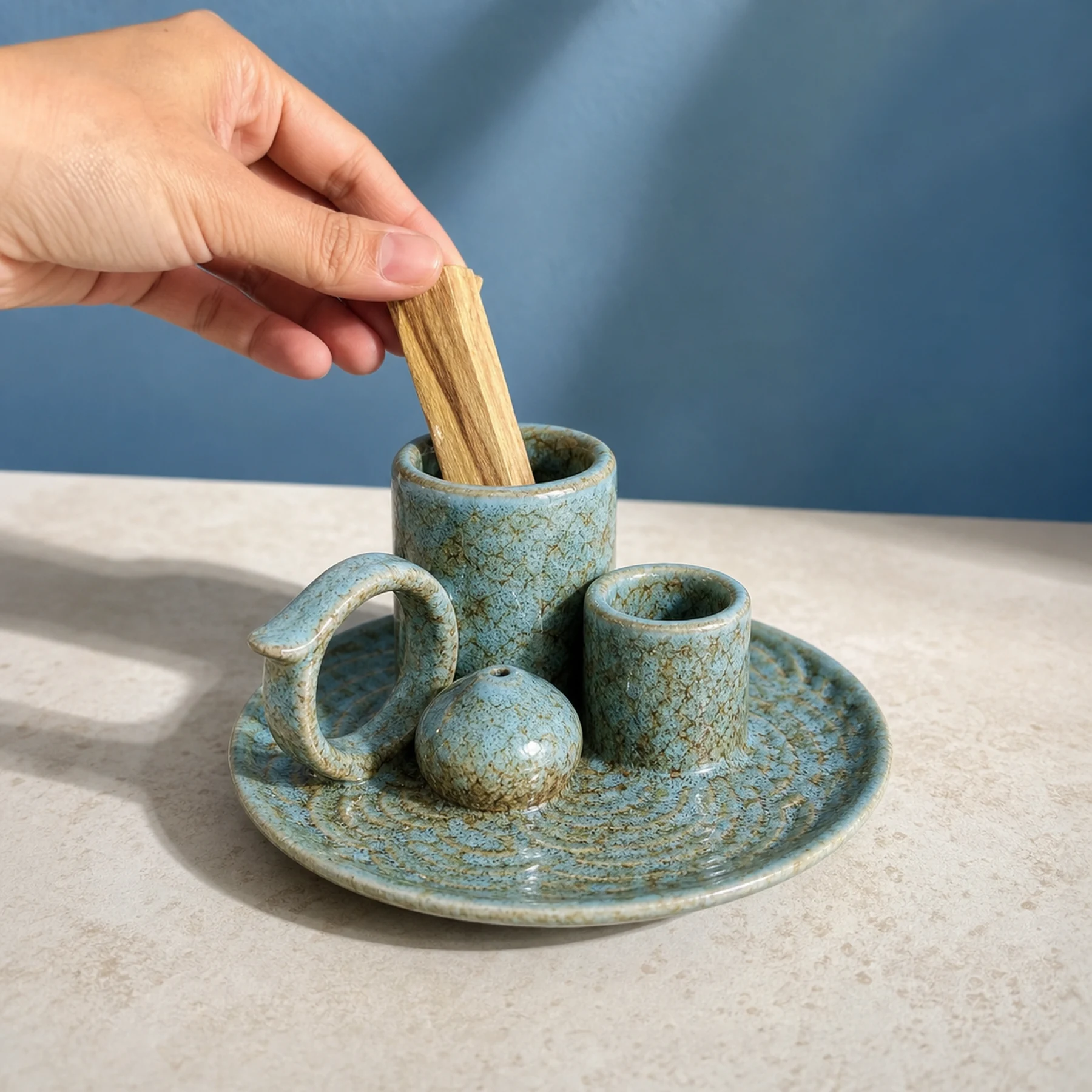 Blue glaze 5-in-1 ceramic smudge bowl shown with an adult hand for tabletop scale