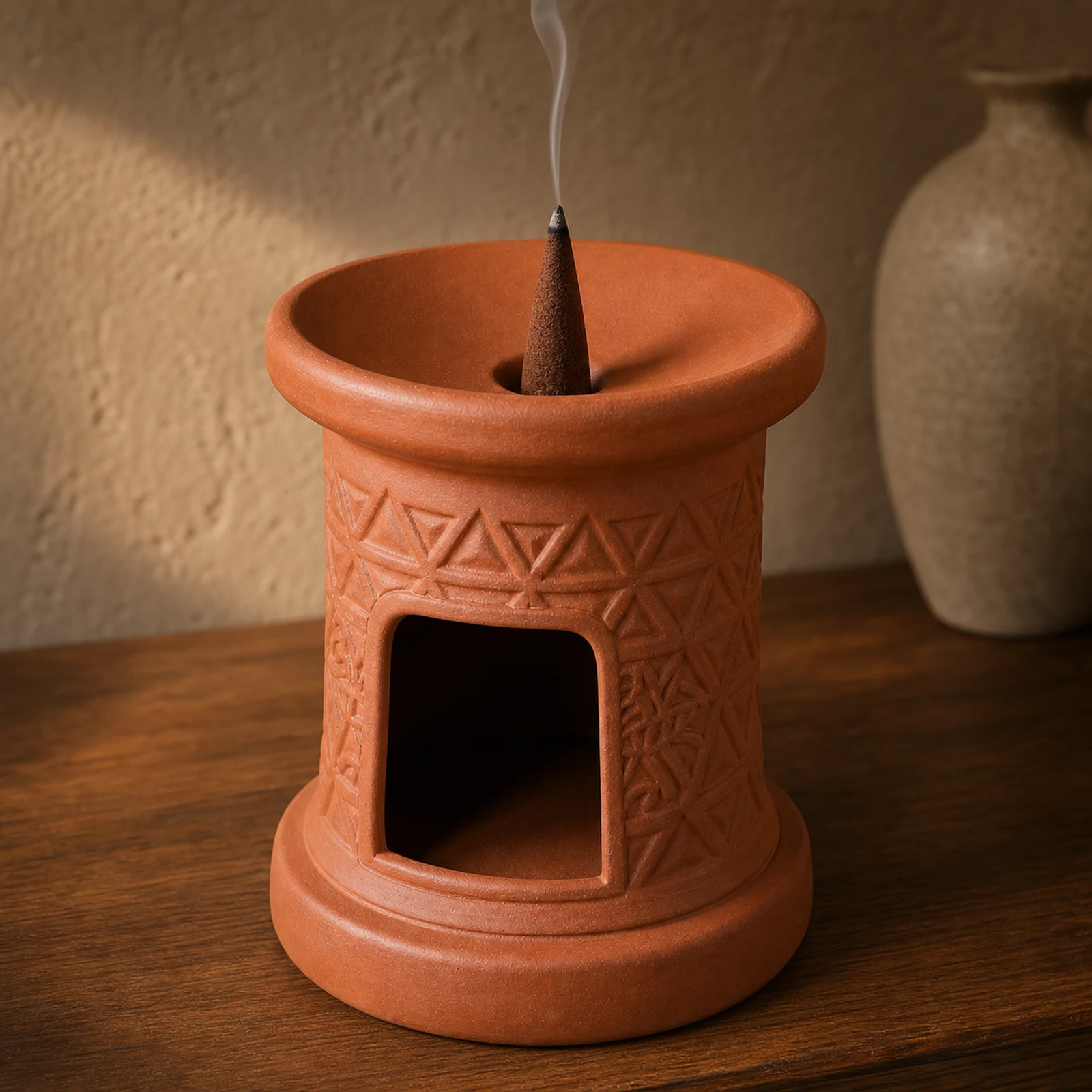 Terracotta incense burner holding a deep brown tapered incense cone with smoke from the cone tip