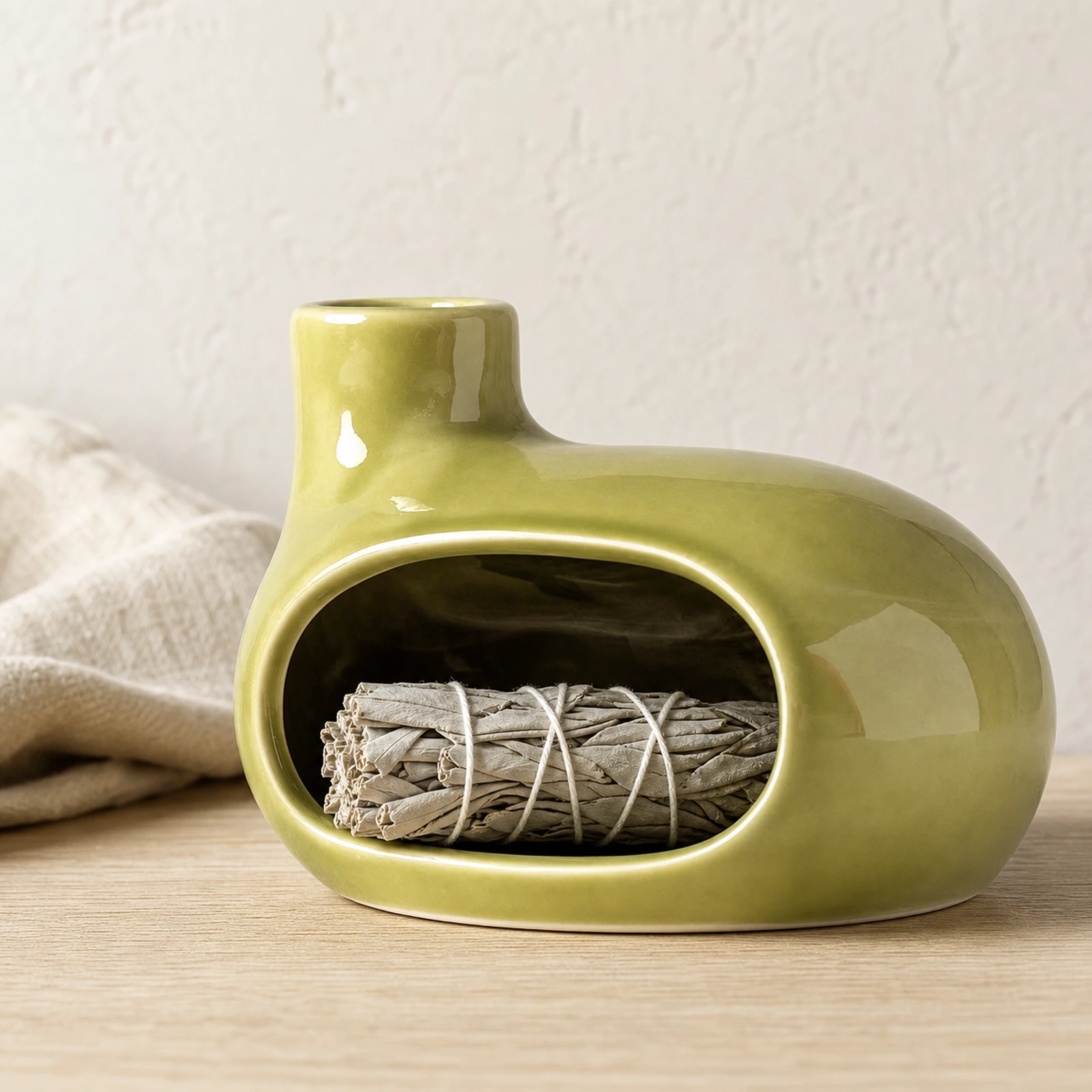 Emerald green Classic Ceramic Palo Santo & Sage Burner, home scene with an unlit white sage bundle in the front chamber.