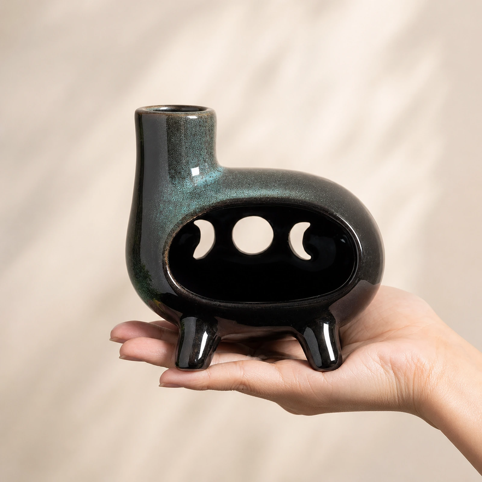 Green glaze four-foot moon-phase Classic Ceramic Palo Santo & Sage Burner, held in an adult hand to show approximate tabletop scale.