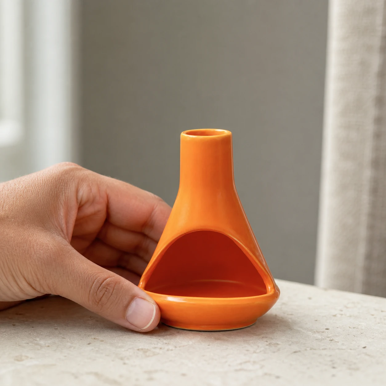 Orange ceramic mini chiminea shown at hand scale