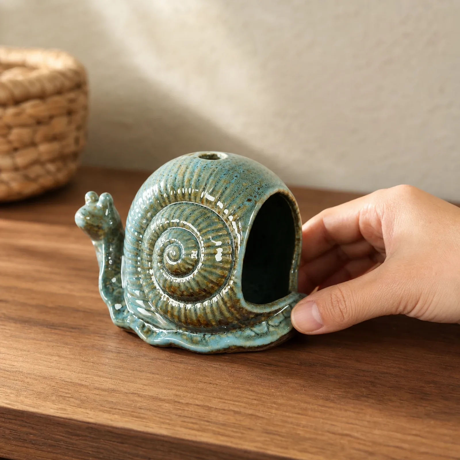 Blue ceramic snail incense holder shown at realistic tabletop hand scale