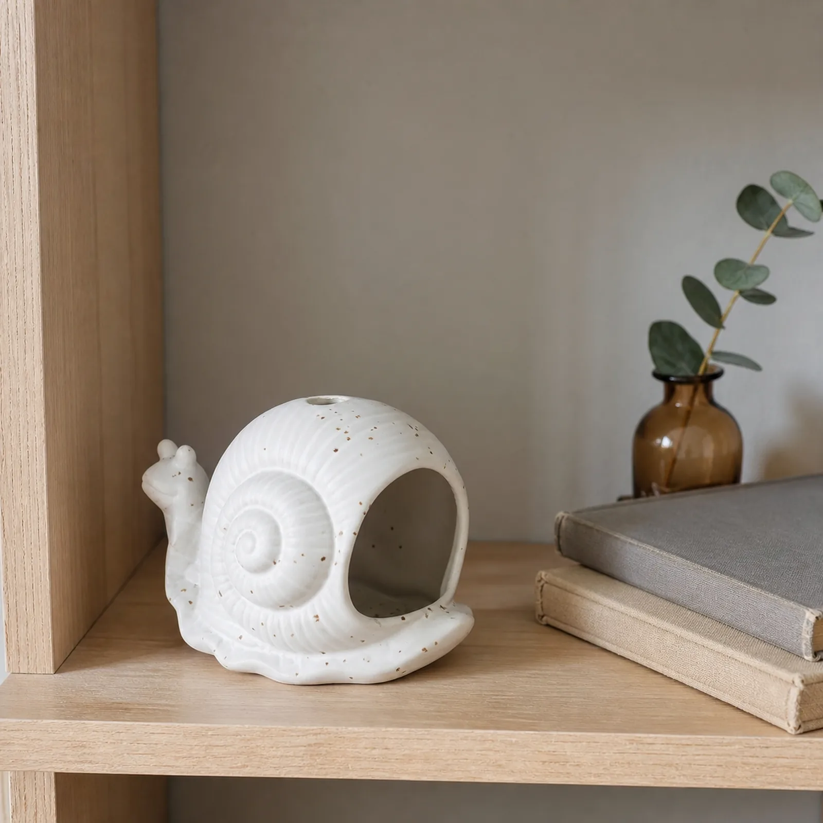 White ceramic snail incense holder styled in an everyday home setting
