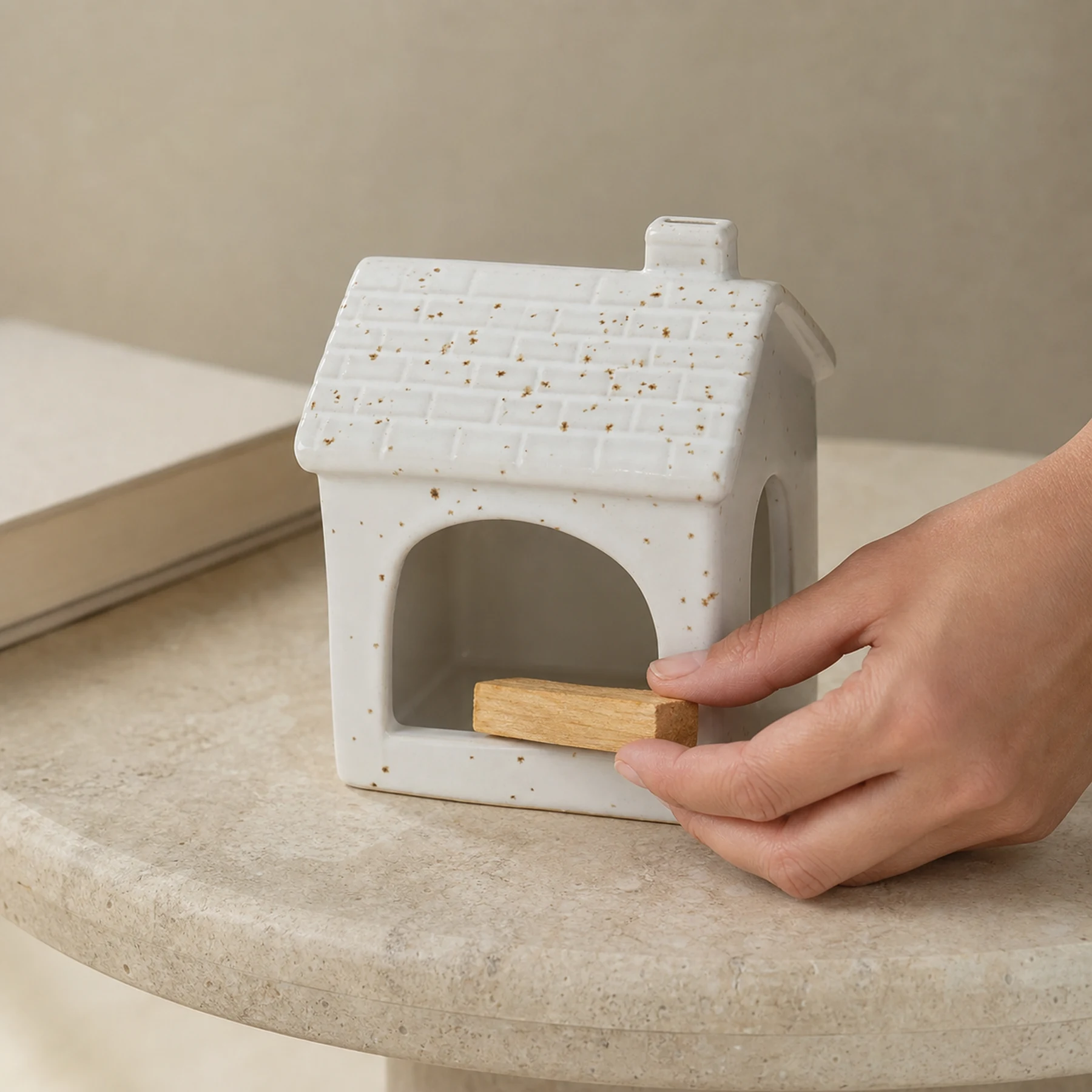 Hand placing unlit Palo Santo into White ceramic house holder for scale