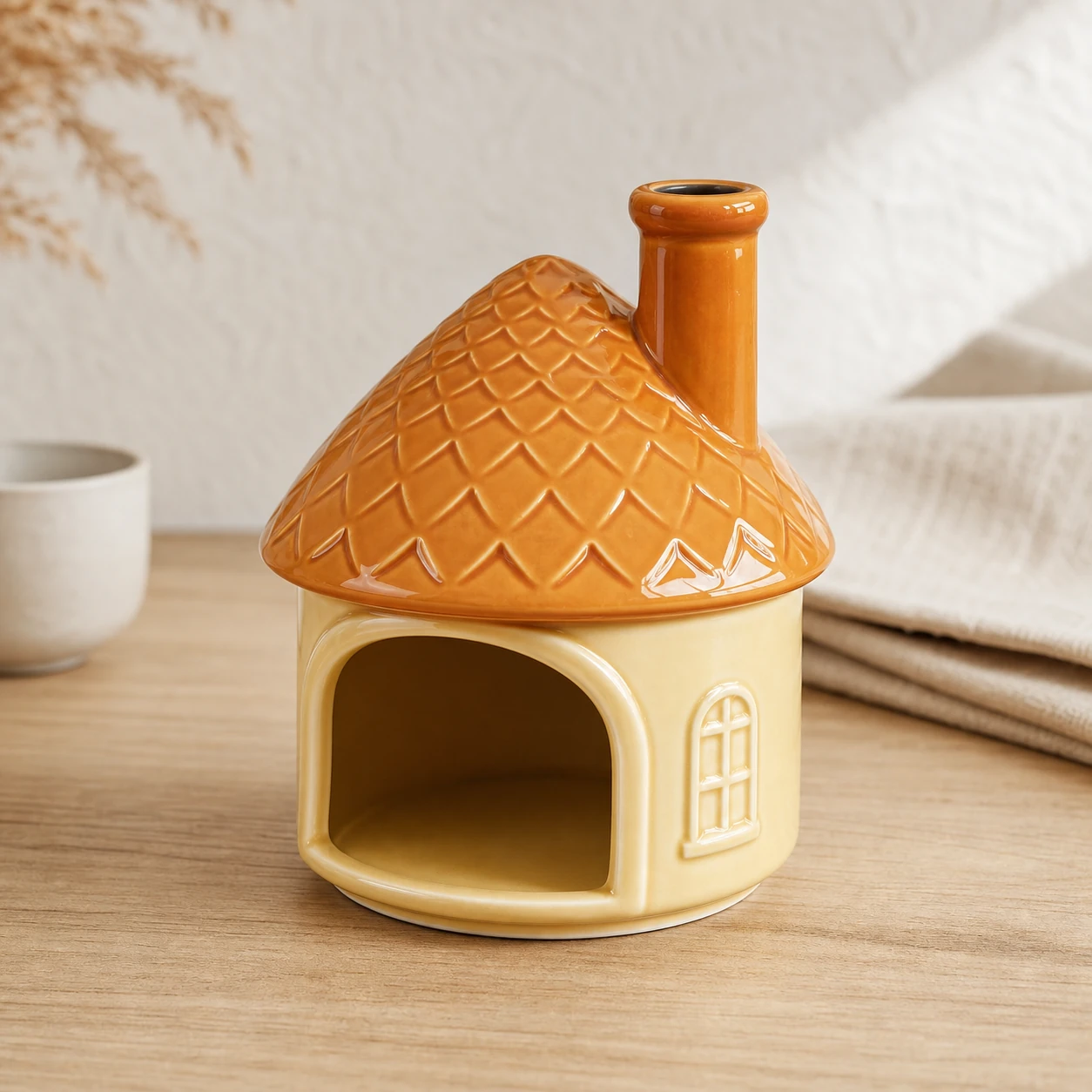 Yellow house ceramic Palo Santo holder clean front-right view on a pale oak console
