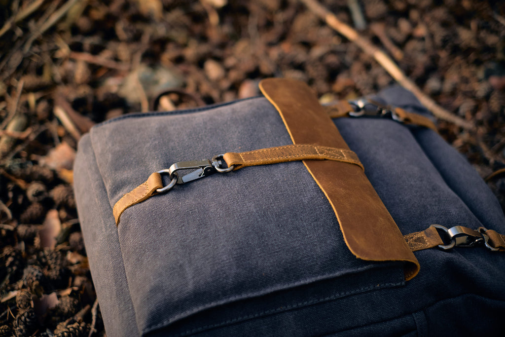 black canvas pack with adjustable shoulder-strap on pinewood