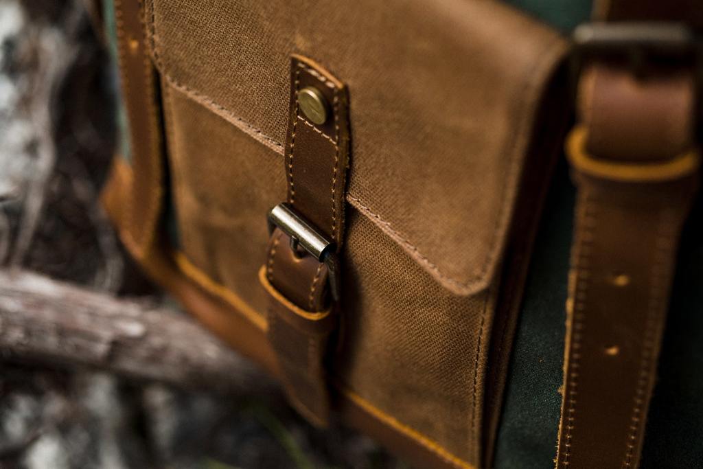 poche avant &agrave; rabat avec boucle magn&eacute;tique d'un sac &agrave; dos homme cuir vintage pos&eacute; sur une branche