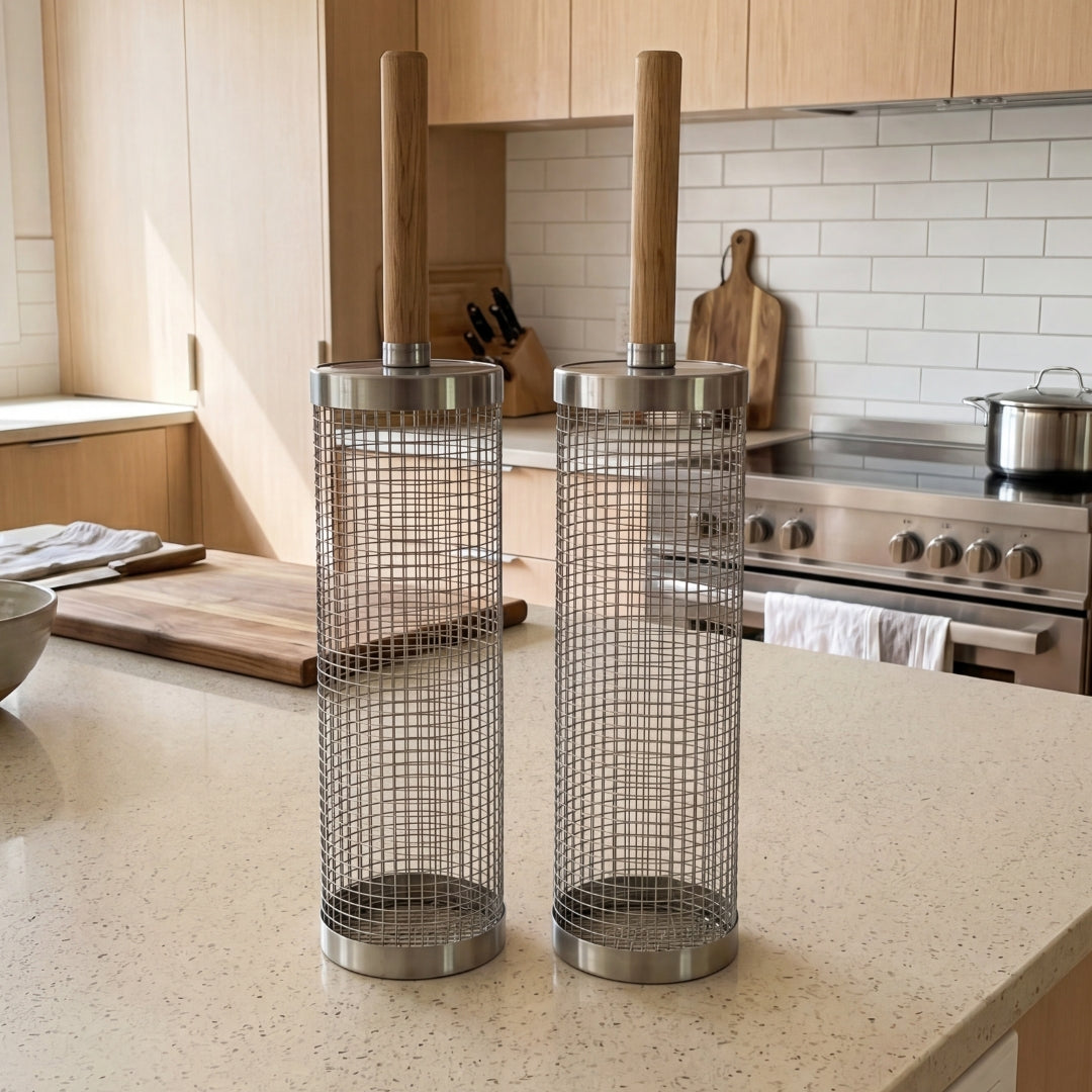 Rolling stainless steel grill baskets with removable wooden handles on a kitchen counter