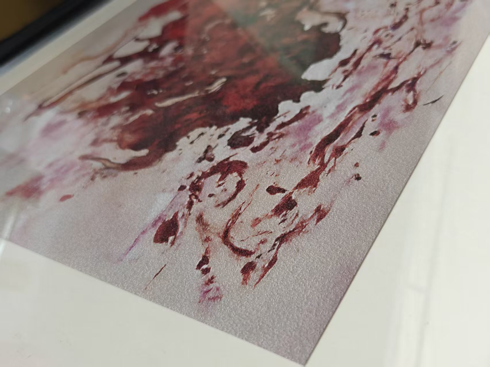 Close photograph of red marks on a Whispart physical print, with its textured surface and pale border visible
