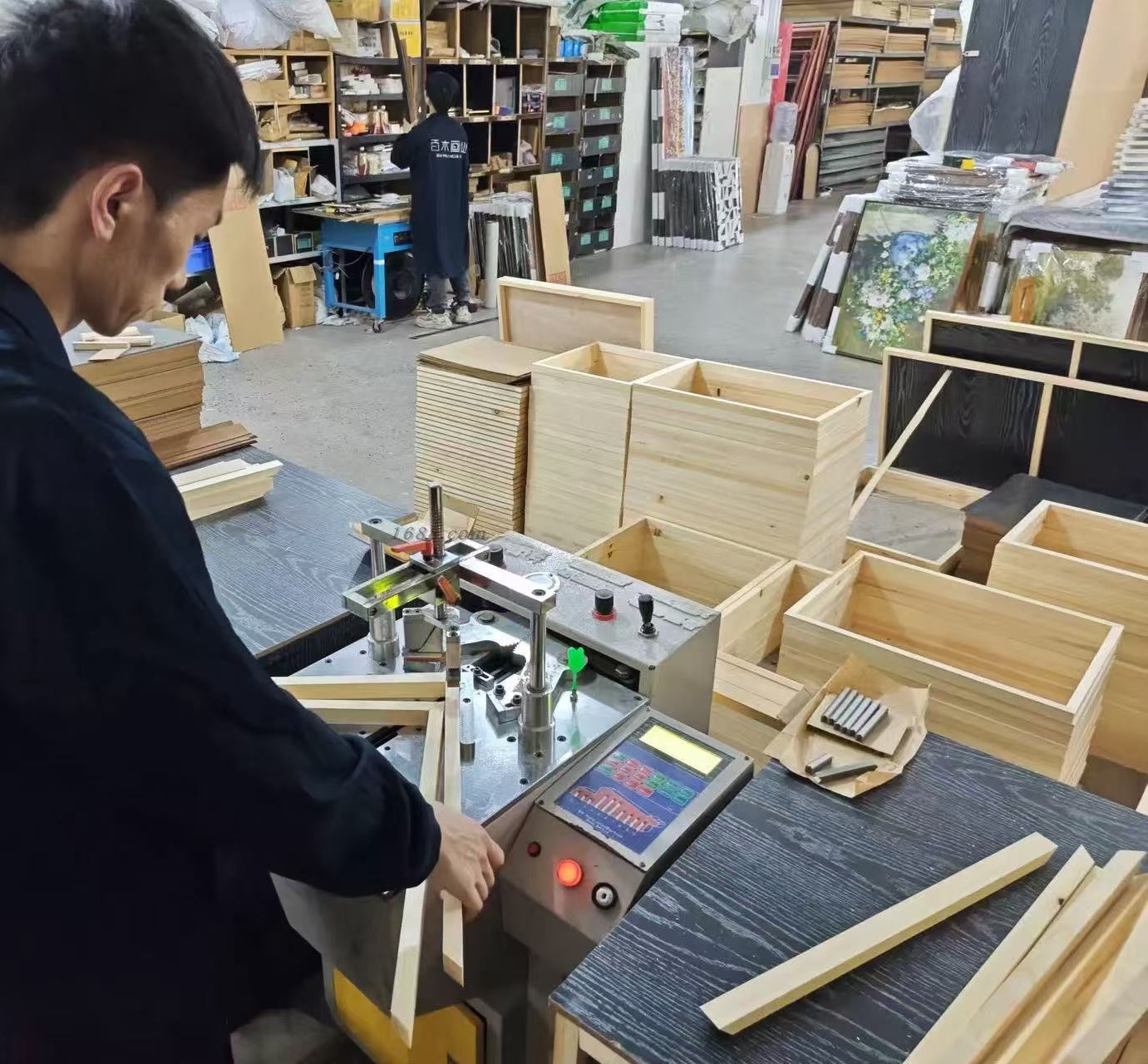 Worker joining frame corners with a corner-nailing machine in the workshop