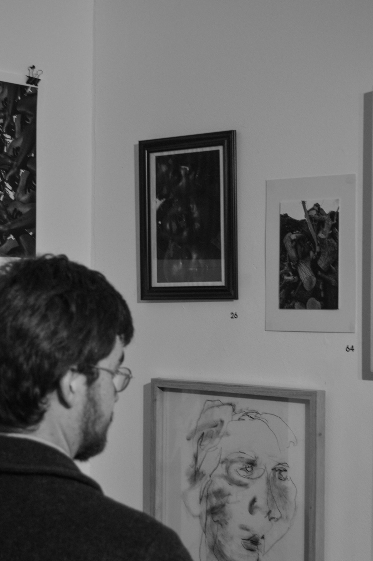 A visitor looks at a wall of framed artworks in a gallery.