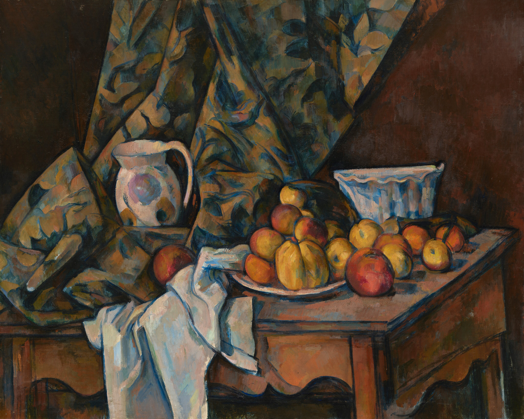 Apples and peaches cluster on a plate and tabletop, beside white cloth, a pale jug and bowl, with patterned fabric hanging behind them.