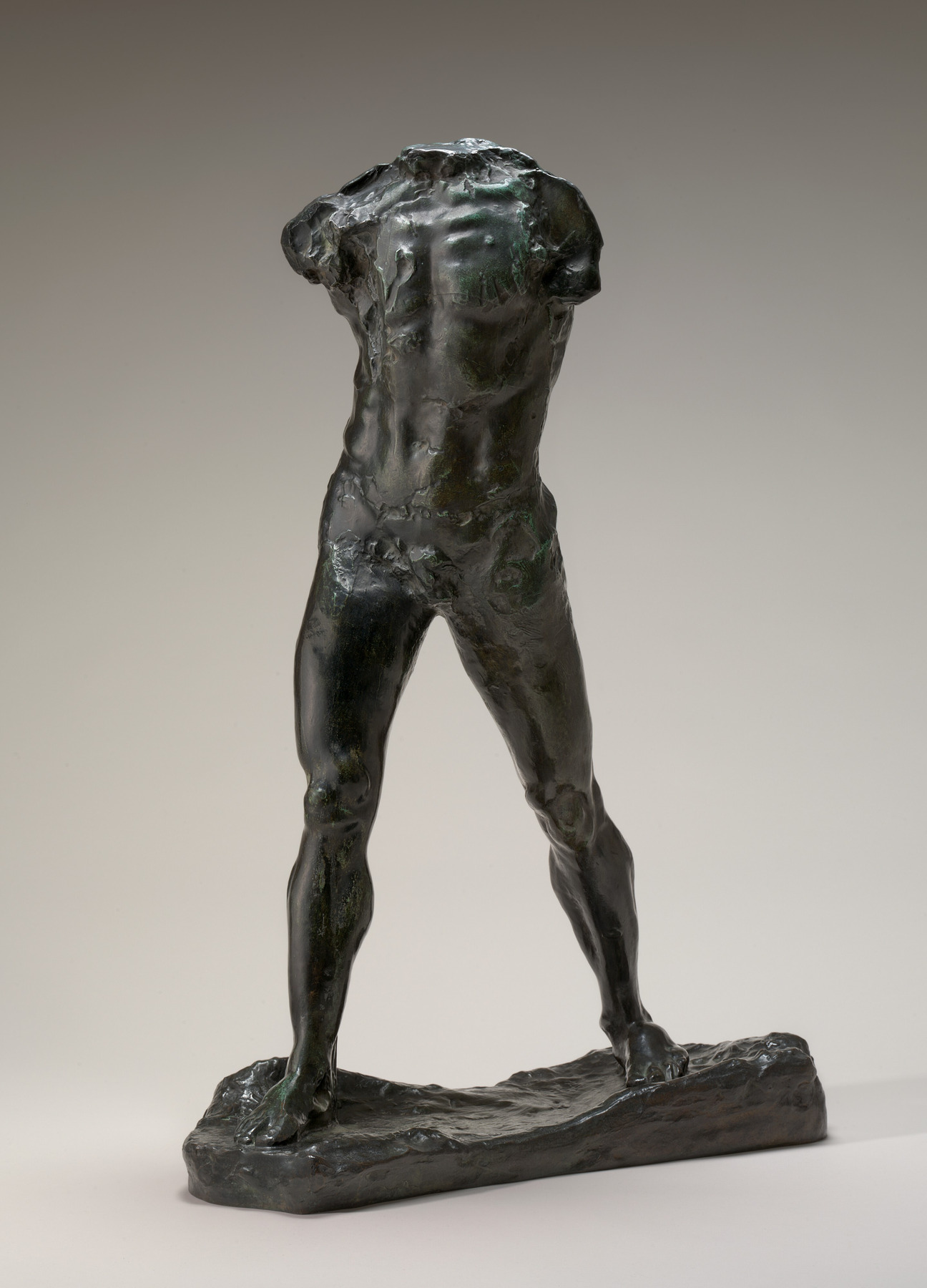 A headless, armless bronze torso stands with its legs apart on a low base, leaving a large opening between them.
