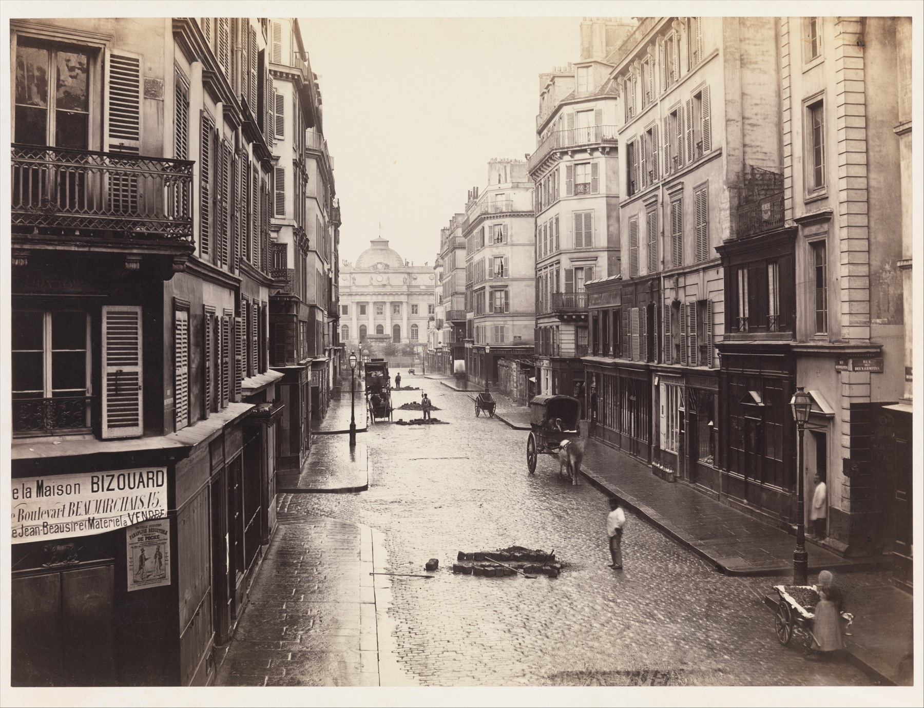 A receding Paris street with pale façades, dark doorways and detailed middle tones in a warm-toned photograph.