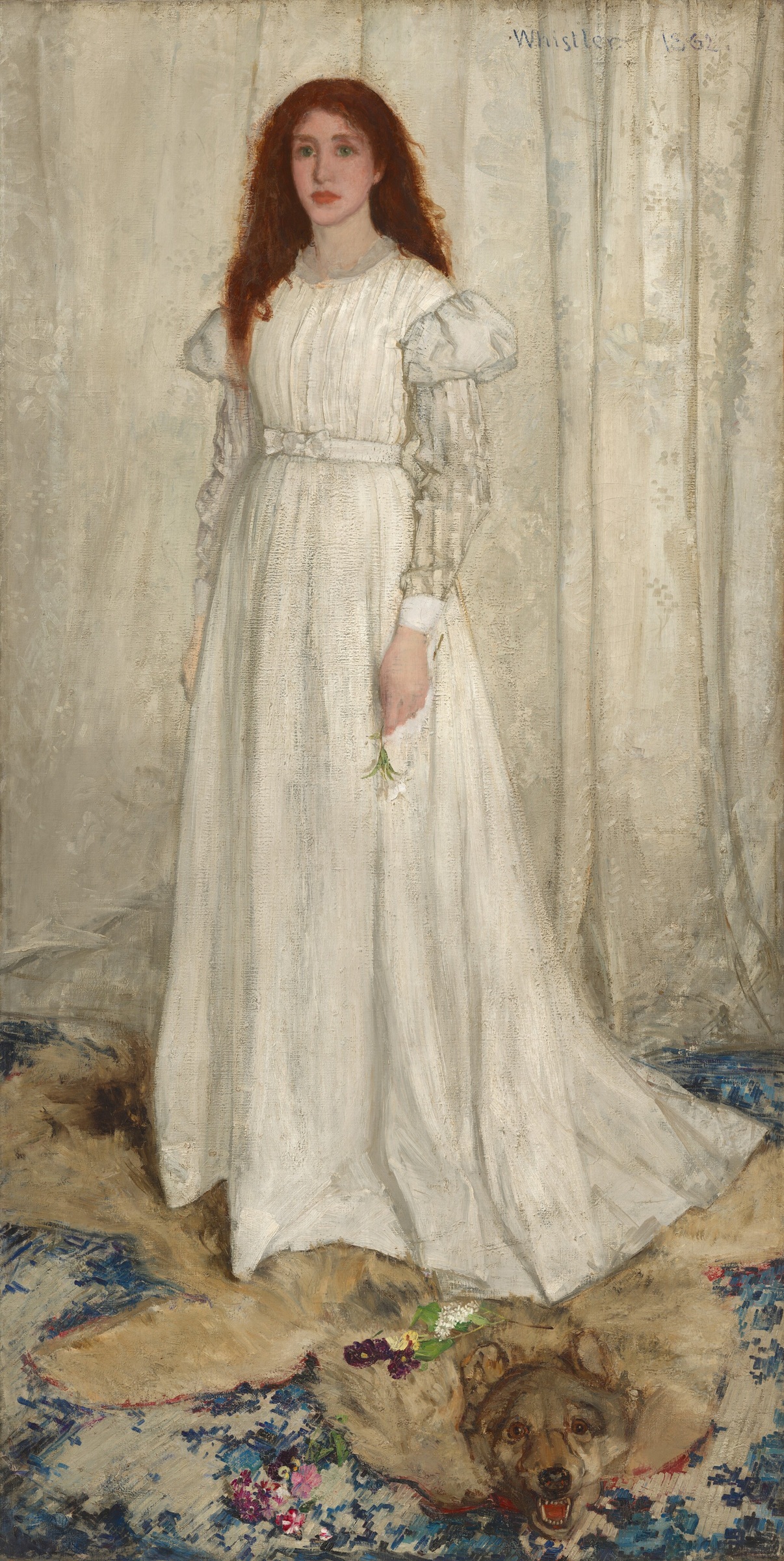 A red-haired woman in a long white dress stands before a pale patterned curtain, on an animal pelt.