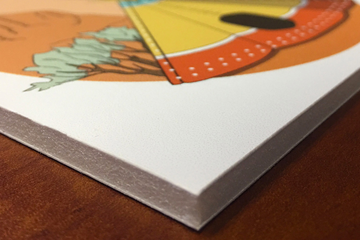 A printed image lies flat on a thick white foam-core board, with the solid board edge visible at the near corner.