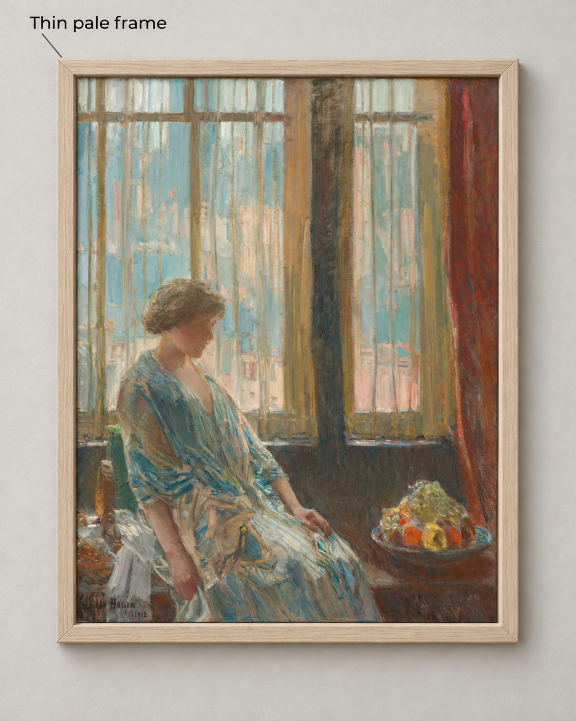 The same Hassam image surrounded by a narrow pale wood frame with visible grain and mitered corners on a pale wall.