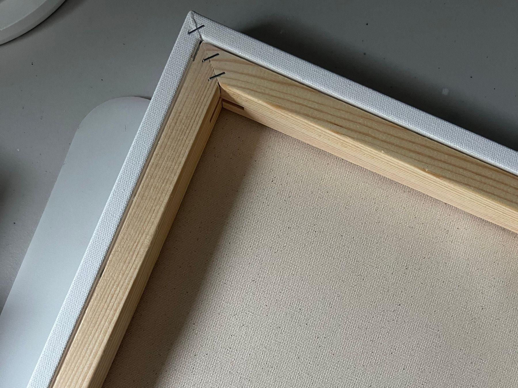 Photograph of the rear corner of a stretched canvas, showing wrapped canvas and wooden stretcher bars.