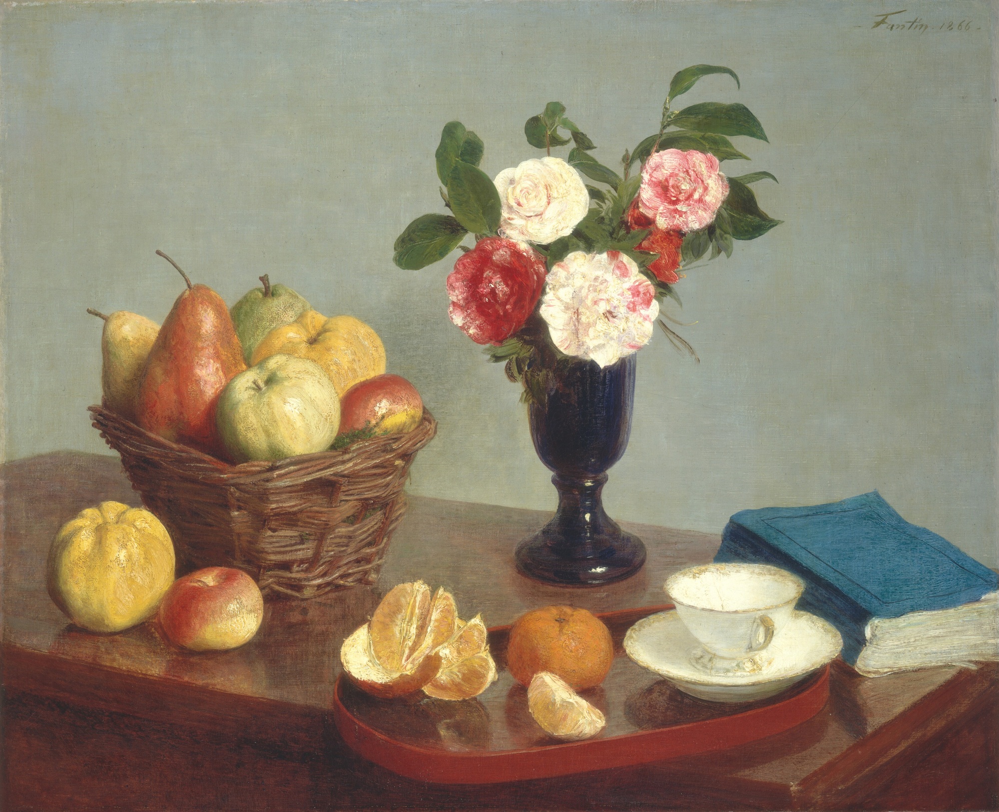 A glass vase of pink and white flowers stands on a polished wooden table with a fruit basket, book, teacup and saucer, and peeled fruit in the foreground.