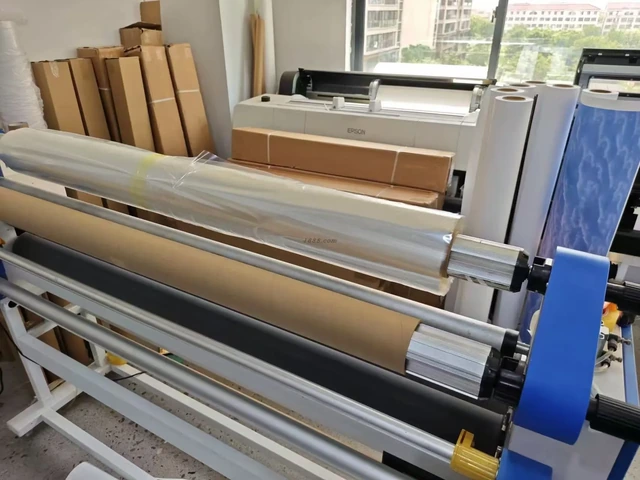 Production workshop with wide-format printing equipment, rolls of material and packing supplies.