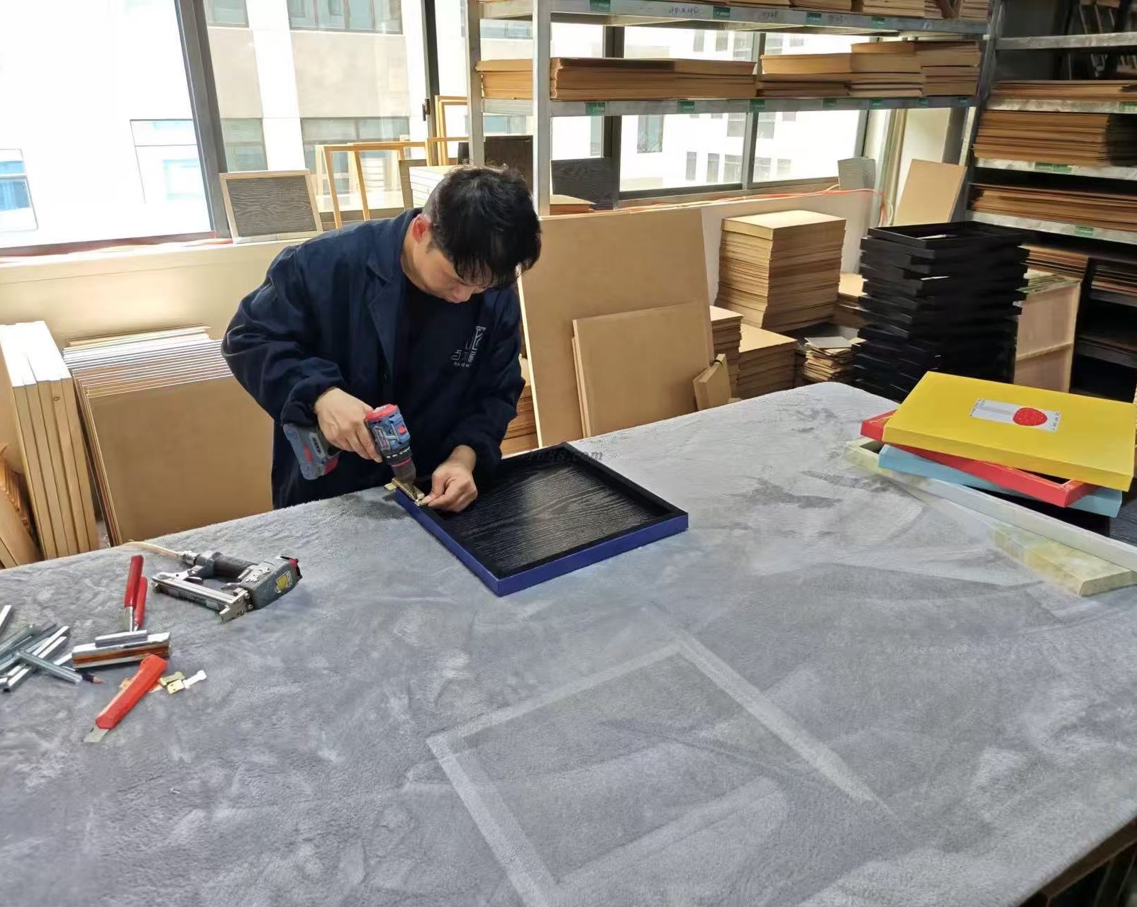 Workshop craftsperson fastening the backboard of a framed work by hand