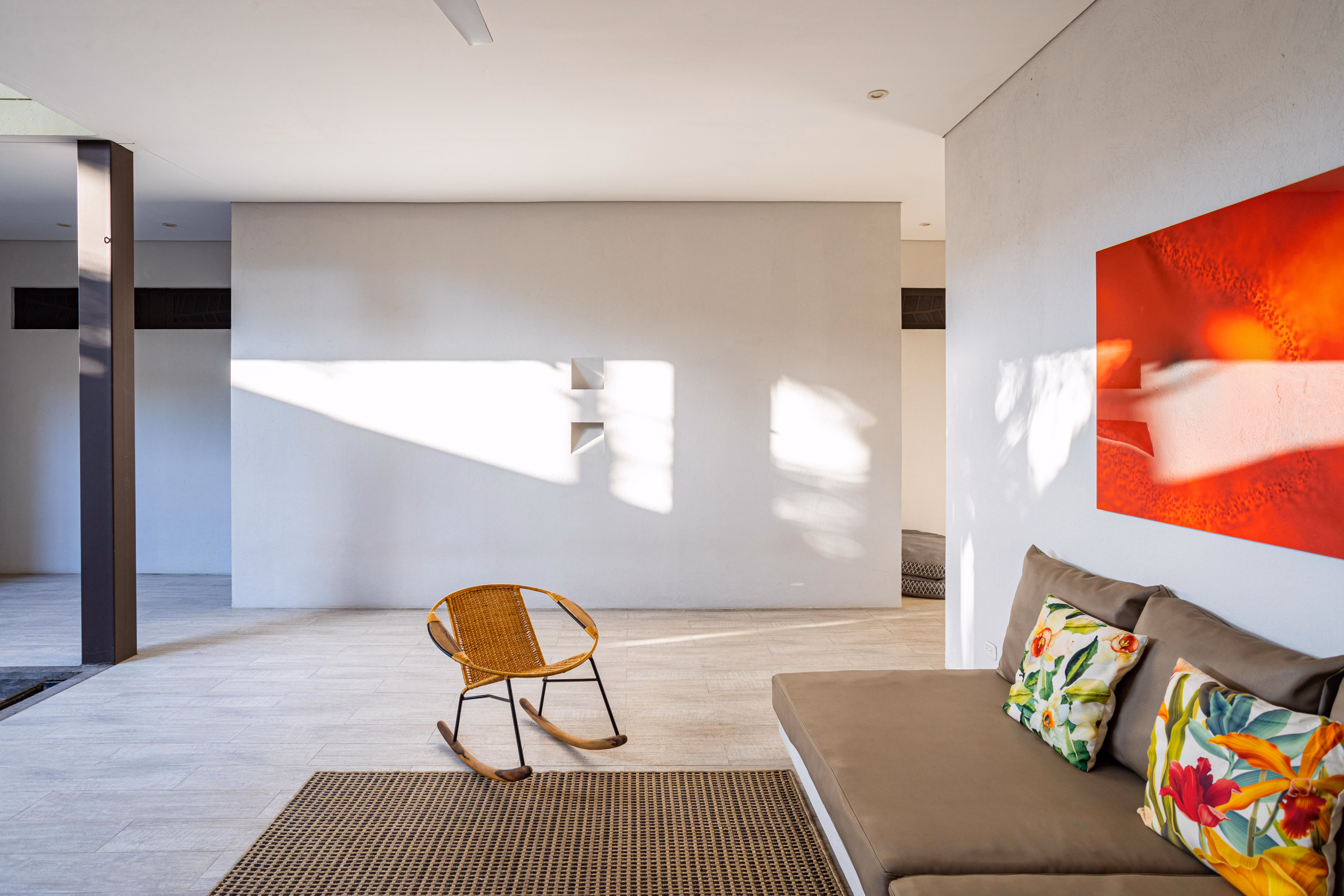 Red abstract painting hung above a gray sofa in a bright minimalist living room.