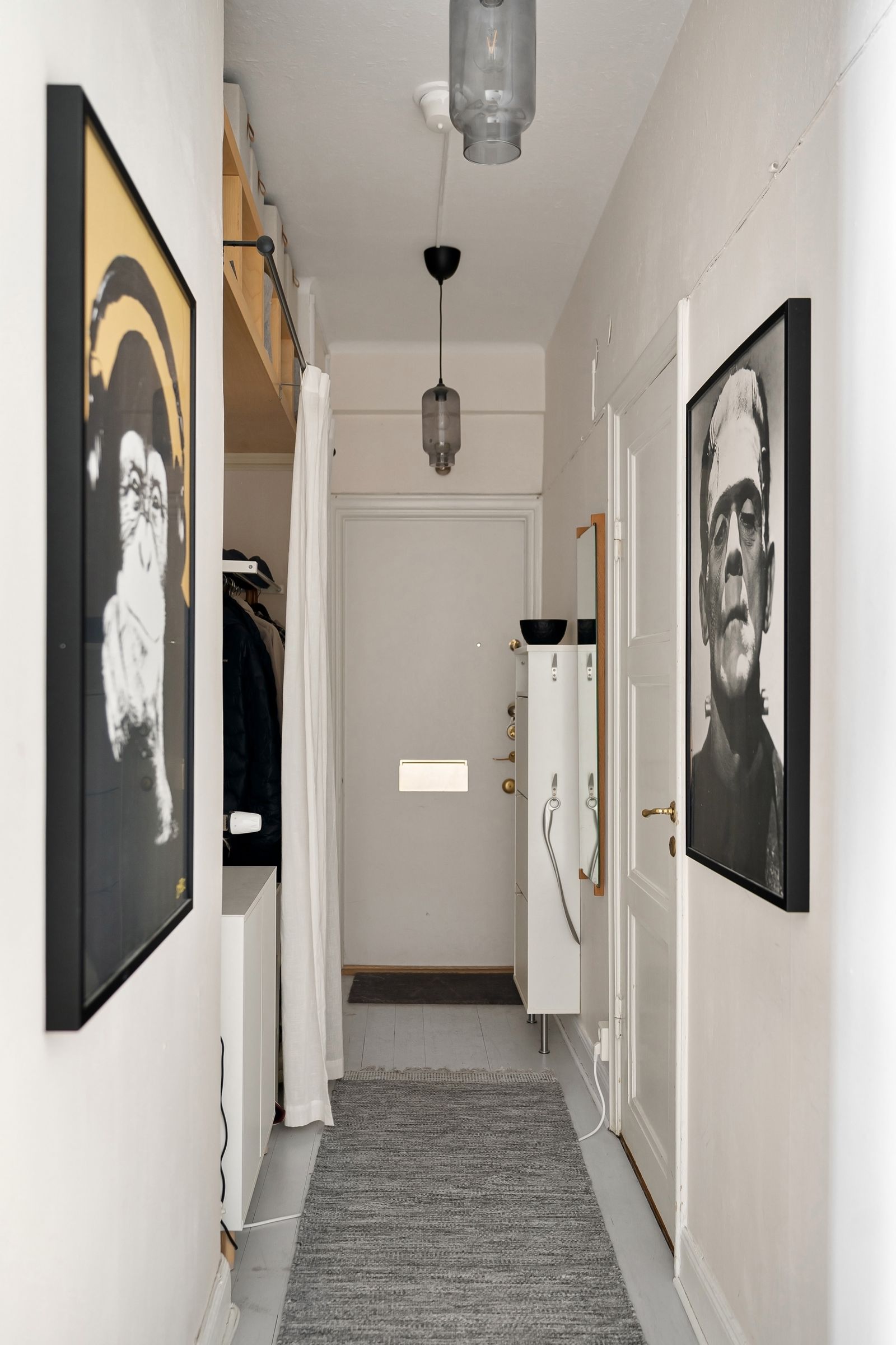 Narrow apartment hallway with framed artwork and storage; Lisa Anna / Pexels.