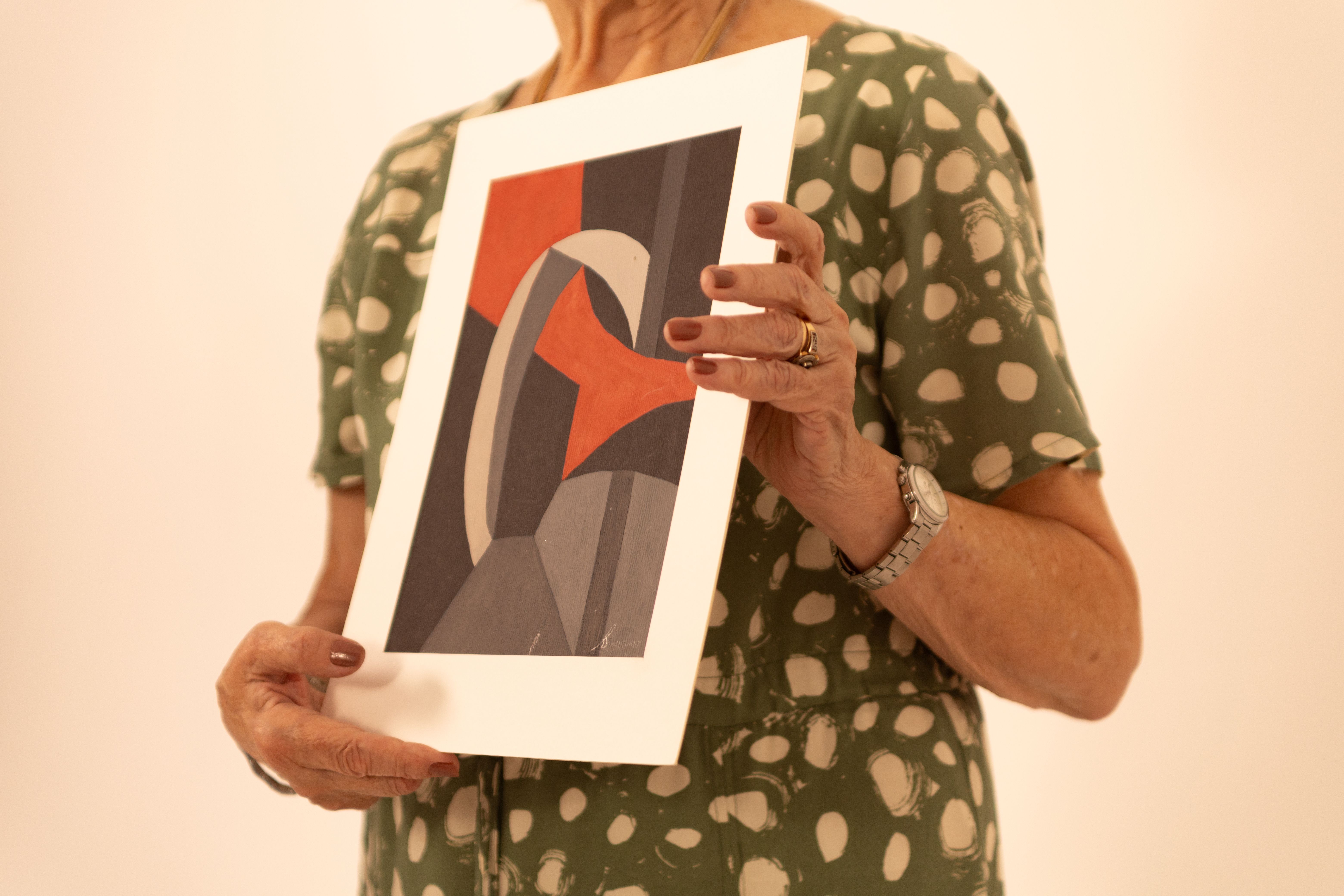 Person holding an abstract art print, representing the moment of comparing a physical artwork before an online purchase.