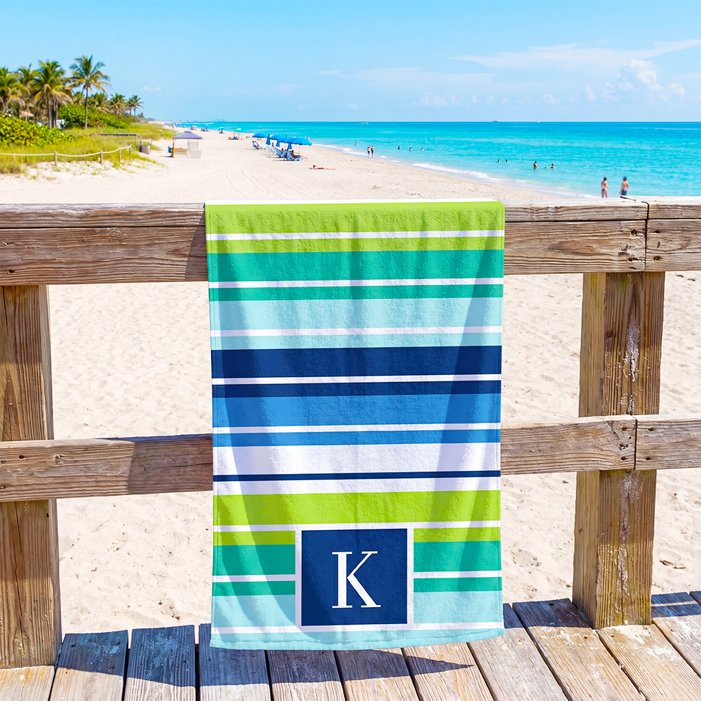 Striped monogram beach towel displayed outdoors with personalized design for beach accessories