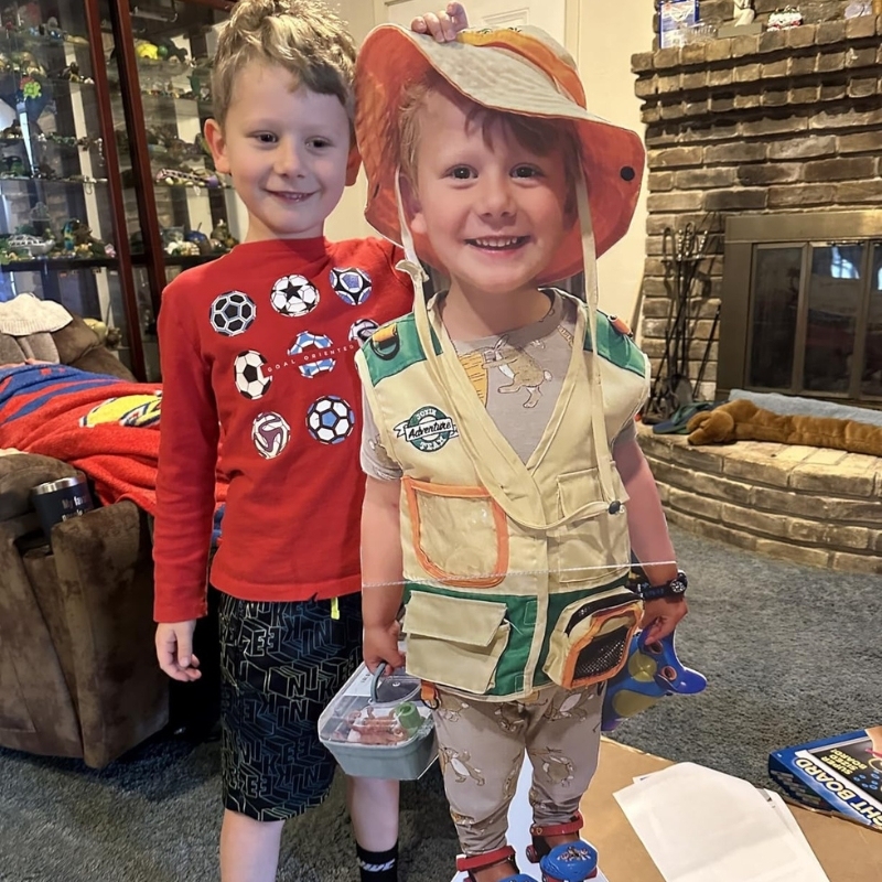 Two young boys, one posing with his brother's life-size cutout in safari outfit