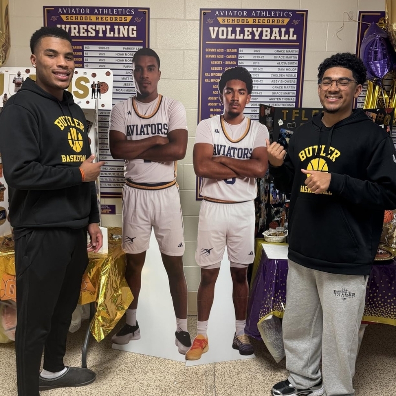 Two basketball player life-size cutouts with Aviators teammates posing in locker room